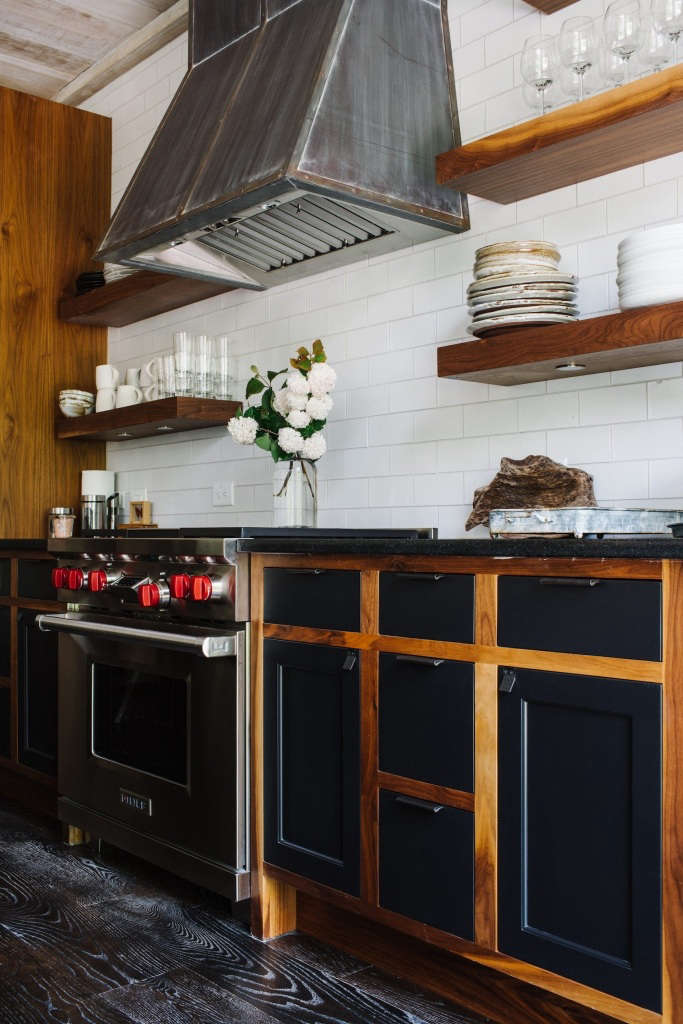 A custom zinc hood hangs above a Wolf range. Chad likes “nice cars and appliances,” the designer says. The flooring is black limewashed wood.