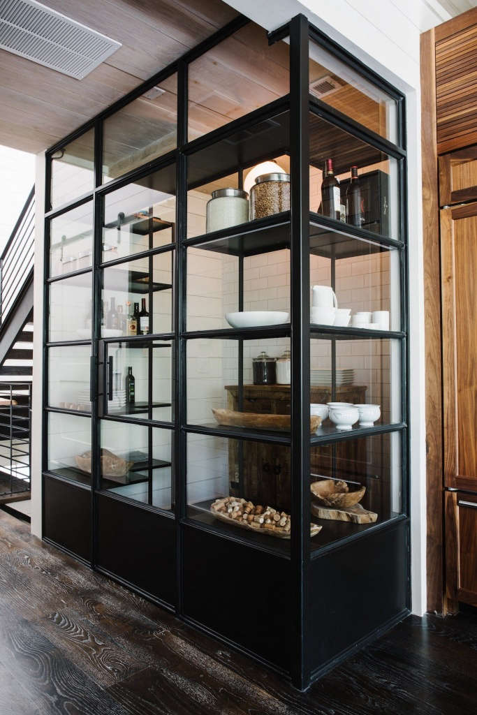 A steel-and-glass pantry is stocked with essentials.