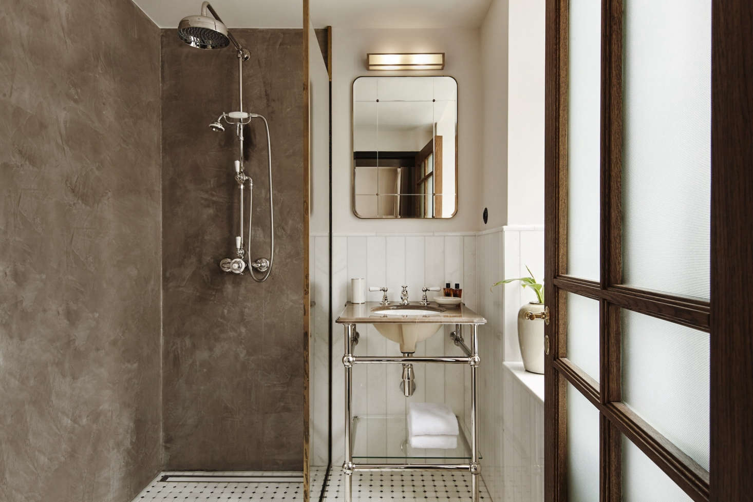 The shower walls are made of warm gray polished plaster and the tiles are all sourced from Greece; the vertically laid tiles are white Thassos marble. The pedestal sink is custom by Aquadomo in Denmark. Photograph courtesy of Lind & Almond.