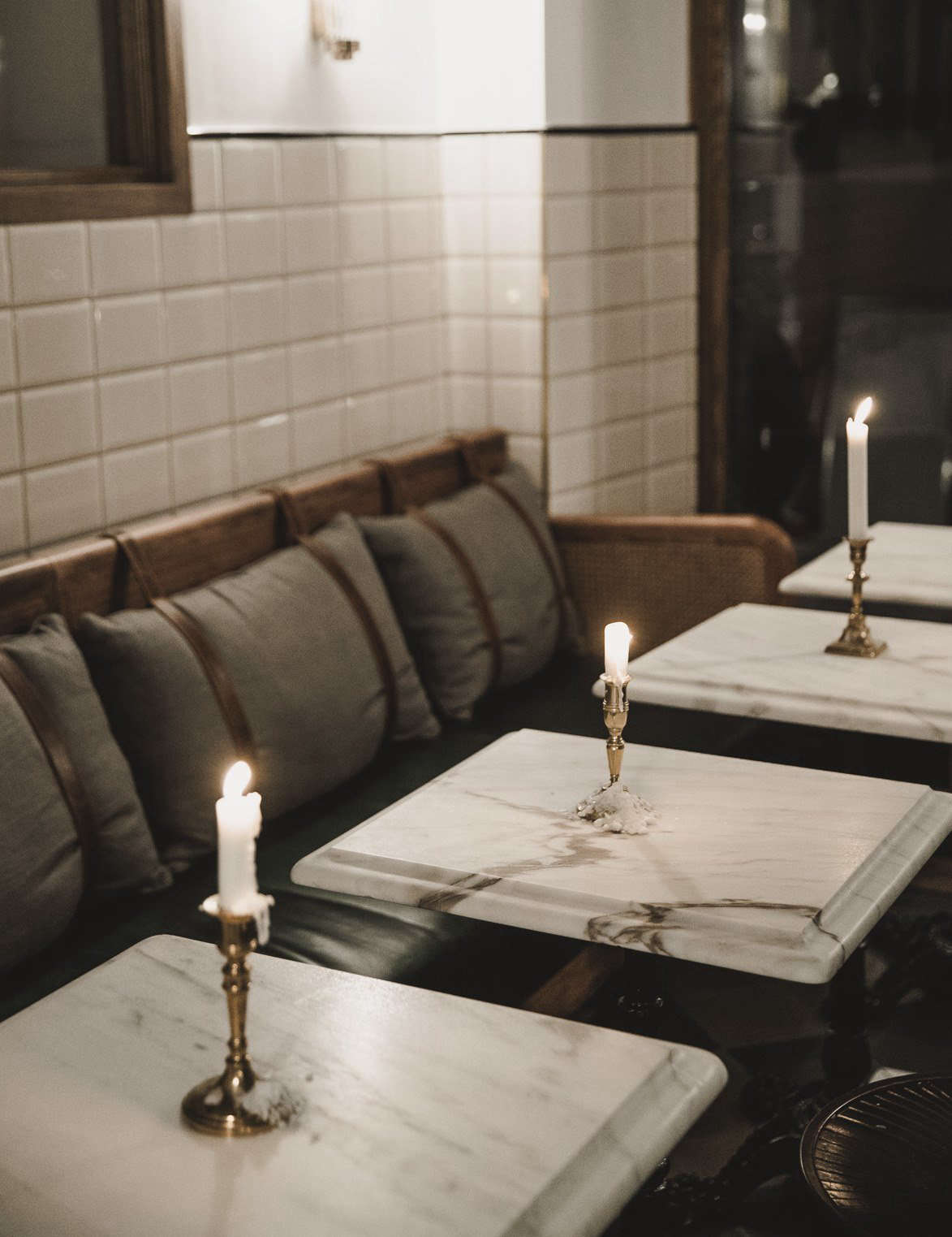 Single brass candlesticks adorn each table—an idea to copy at home.