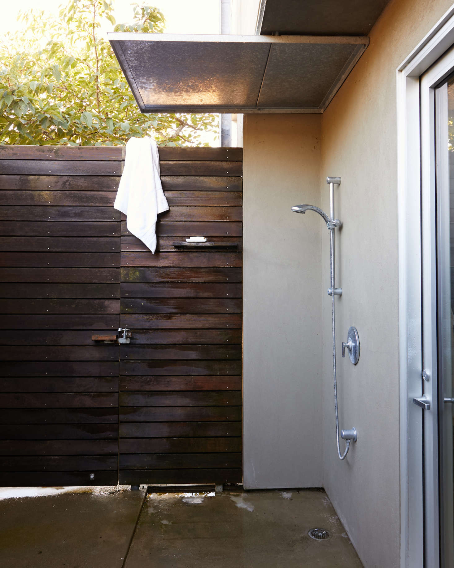 An outdoor shower lined in stucco and redwood off the back door from the master bath.