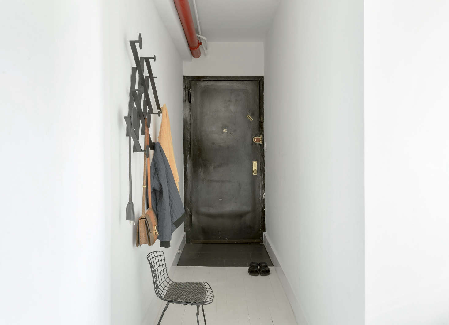 Off the entry, a Dante Memoir Accordion Coat Rack from Garde LA provides hooks at the perfect heights for all family members. The wire chair is a vintage Harry Bertoia.