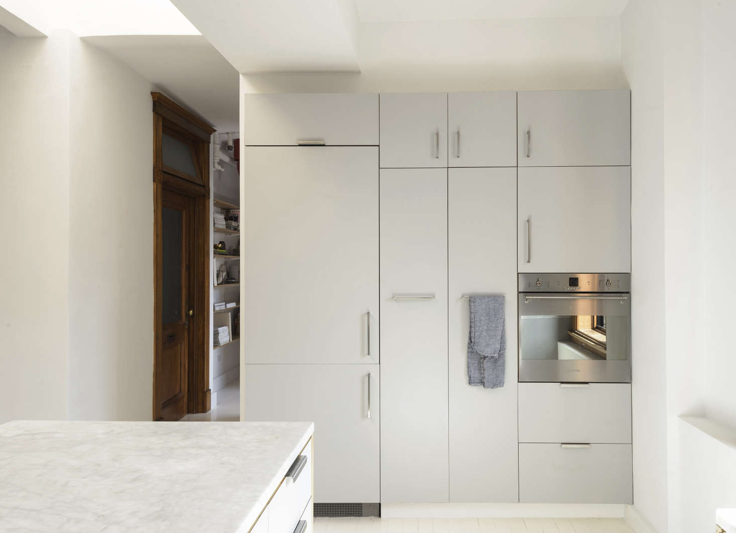 The fridge is concealed on the cabinet wall, which incorporates a Smeg wall oven.