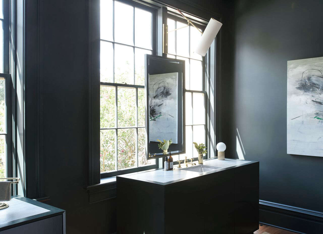 A custom vanity mirror mounted to the window frame. The designers created a bath consoles with custom stone tops and matching paint color. Photograph by Matthew Williams from Southern Modern in Charleston: A Fresh Take on the Old South from Workstead.