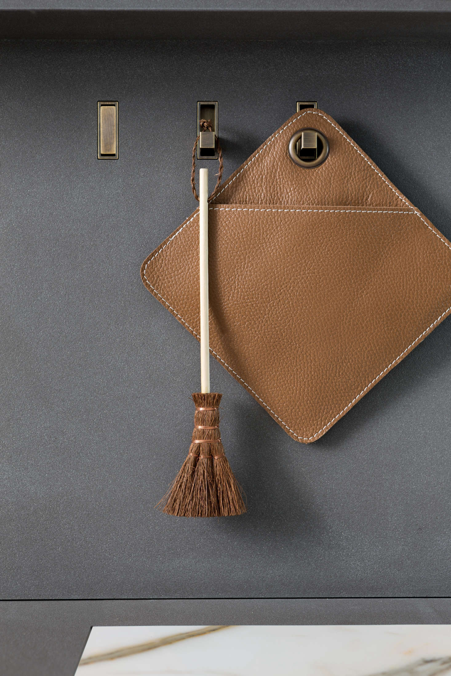 Retractable brass “secret hooks” hold elevated versions of the kitchen essentials. Admiring the potholder? See 5 Favorites: Rugged Leather Potholders.