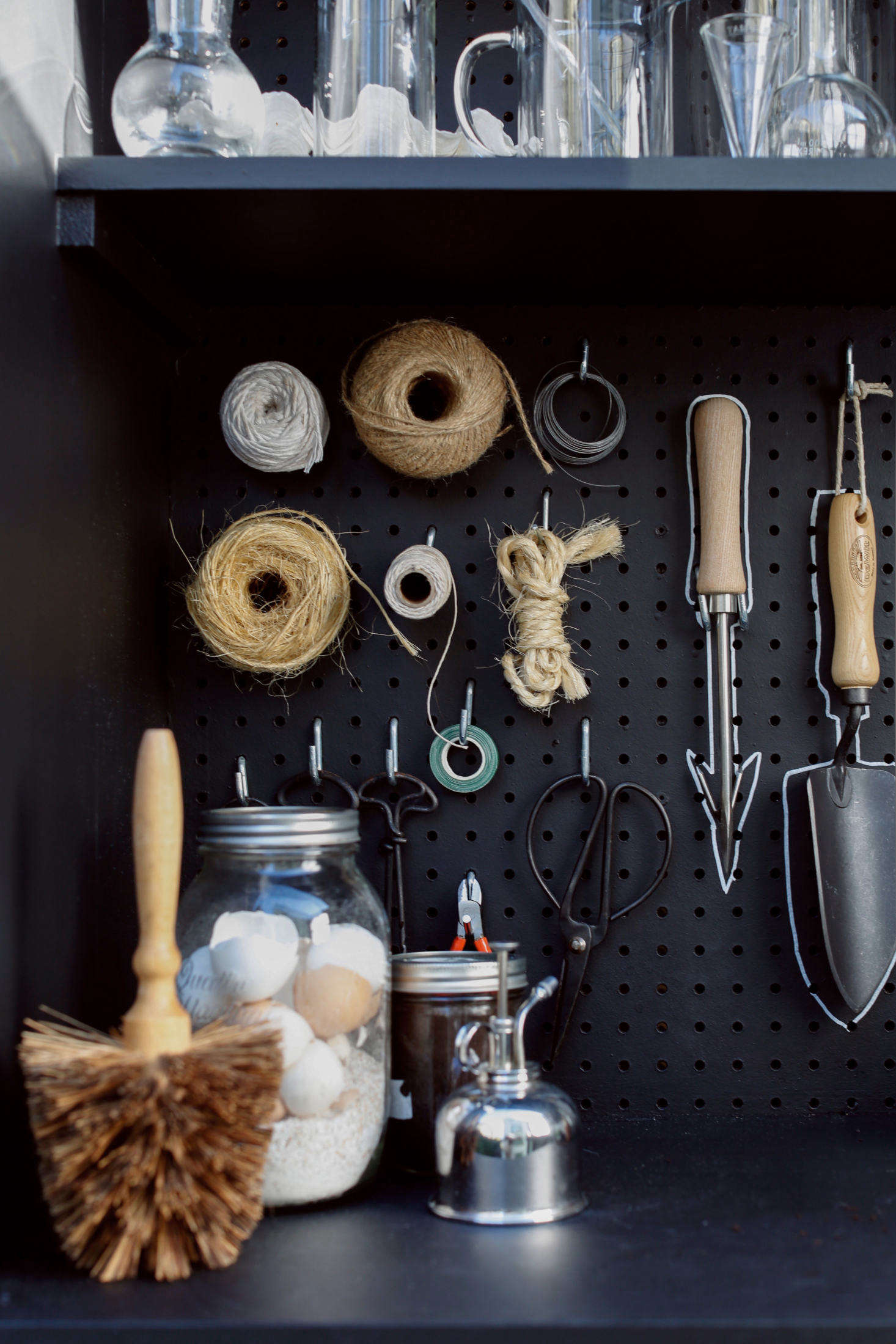 A corner of the shed holds a flowerpot brush, a plant mister, and a jar of eggshells. (Why the eggshells? See Gardening data-src=