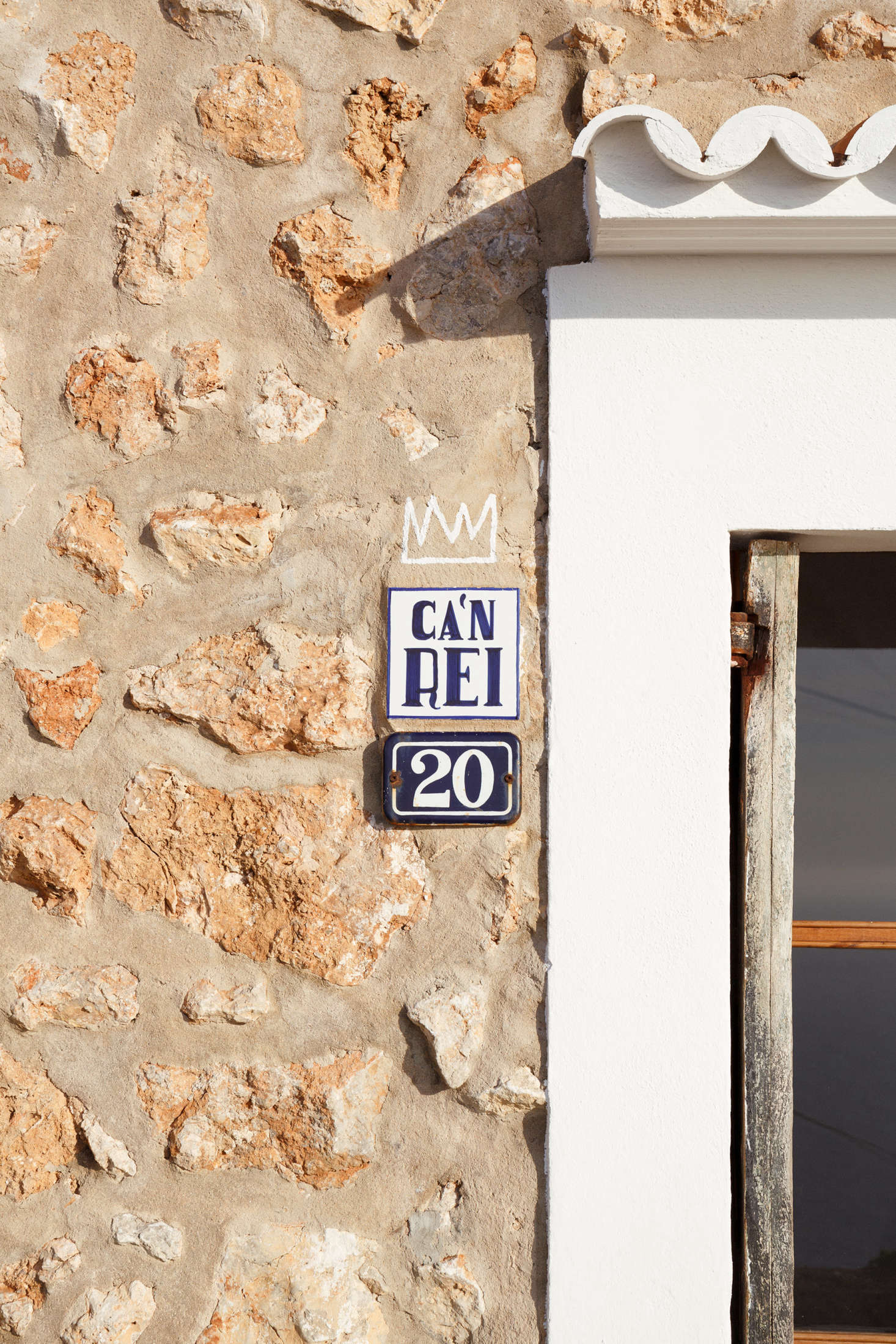 A small sign next to the door announces the house’s name. “In ‘Mallorquin,’ the local dialect of Catalan, ‘ca’n’ means ‘house of’ and ‘rei’ means ‘king,’ although it’s more likely that Rei was a family name rather than being the house of a real king,” the architects explain. “The house had that name for a really long time and everyone in the village knows the house by this name, so there was no point of renaming it.” A hand-drawn crown underscores the point.