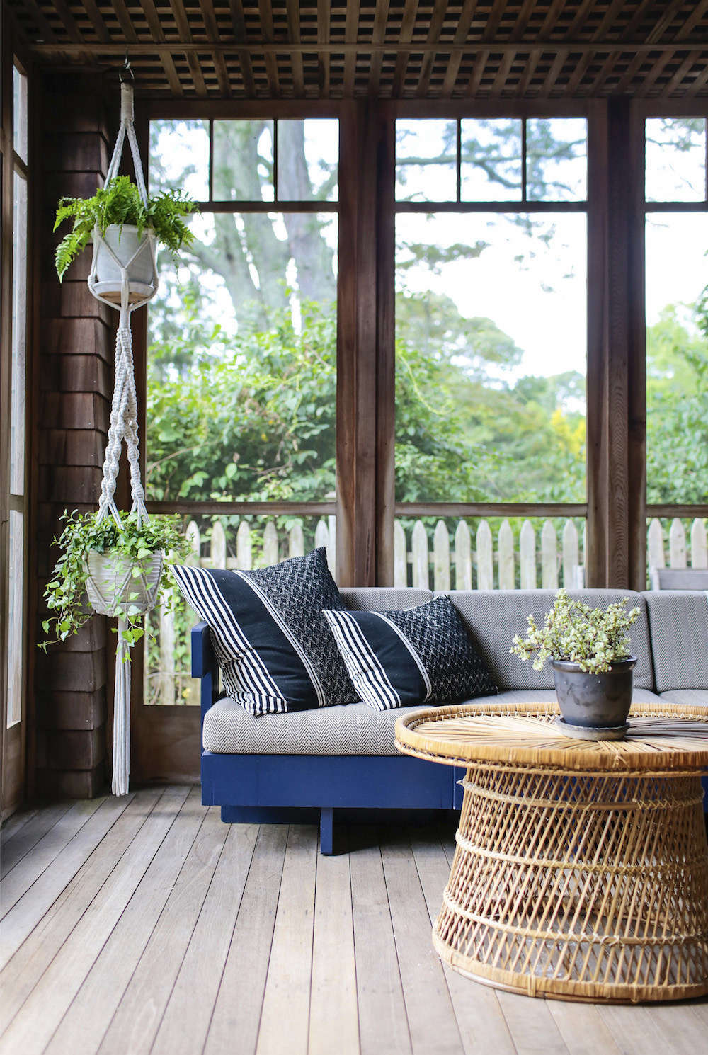 Elizabeth bought the sun porch sofa at auction and had it painted blue and reupholstered. The macramé plant holder is from CB2.