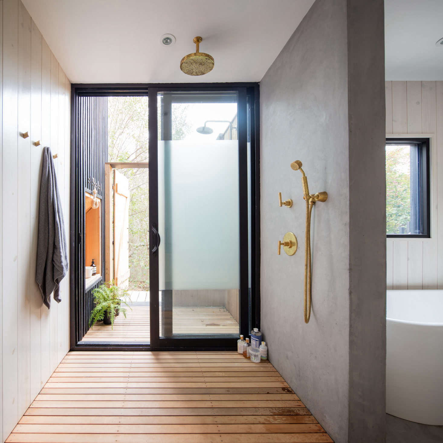The ground-floor bath serves three bedrooms. It has both an indoor and outdoor shower, divided by an obscured-glass sliding door. The outdoor shower can be accessed from the side yard, so residents can have a post-beach rinse without coming indoors.