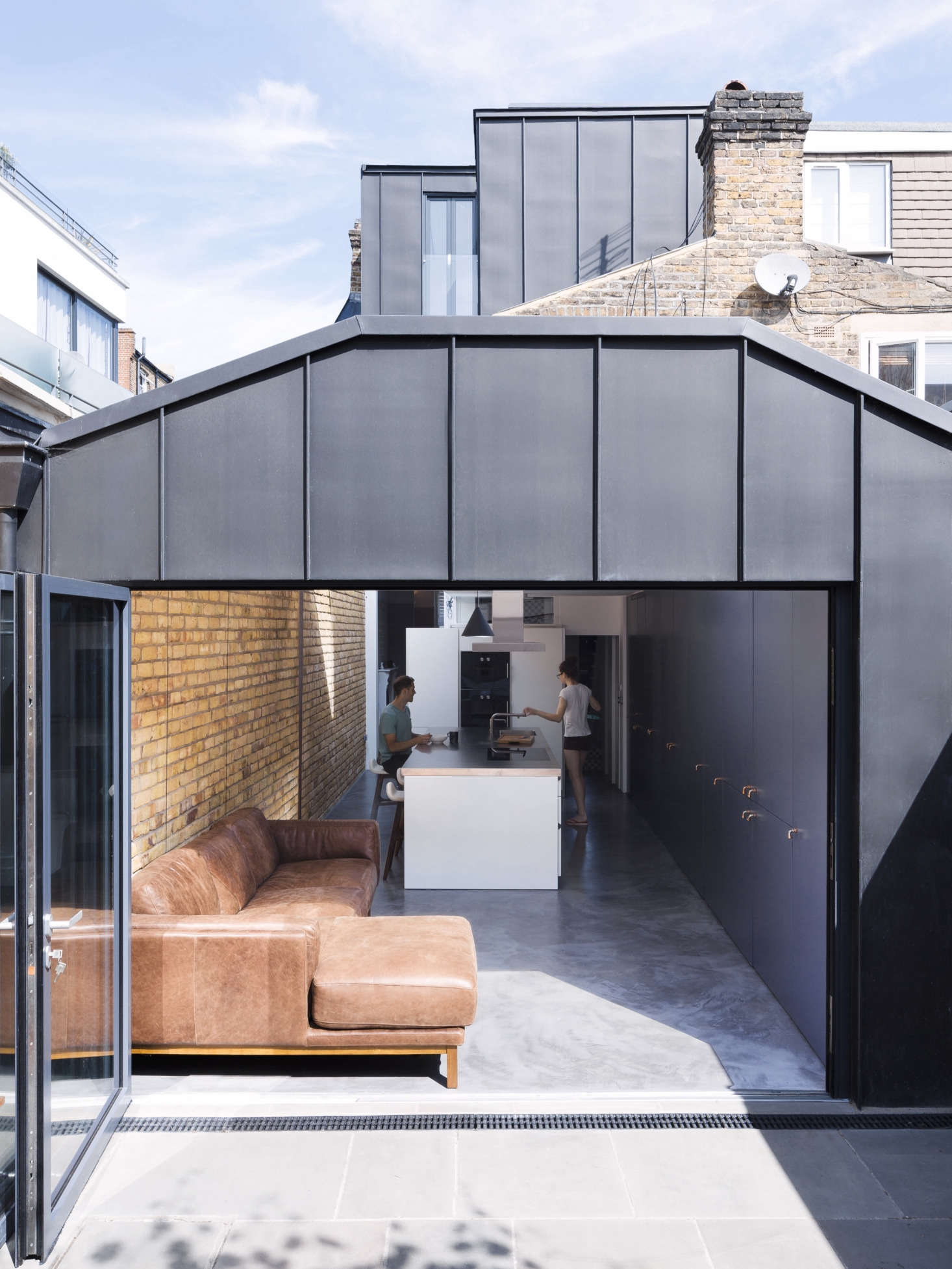 In the back of the house, in place of a small porch (scroll to the bottom for a Before shot), Astridge built a 350-square-foot kitchen/sitting area extension with an accordion steel-frame door that opens onto the terrace and garden.