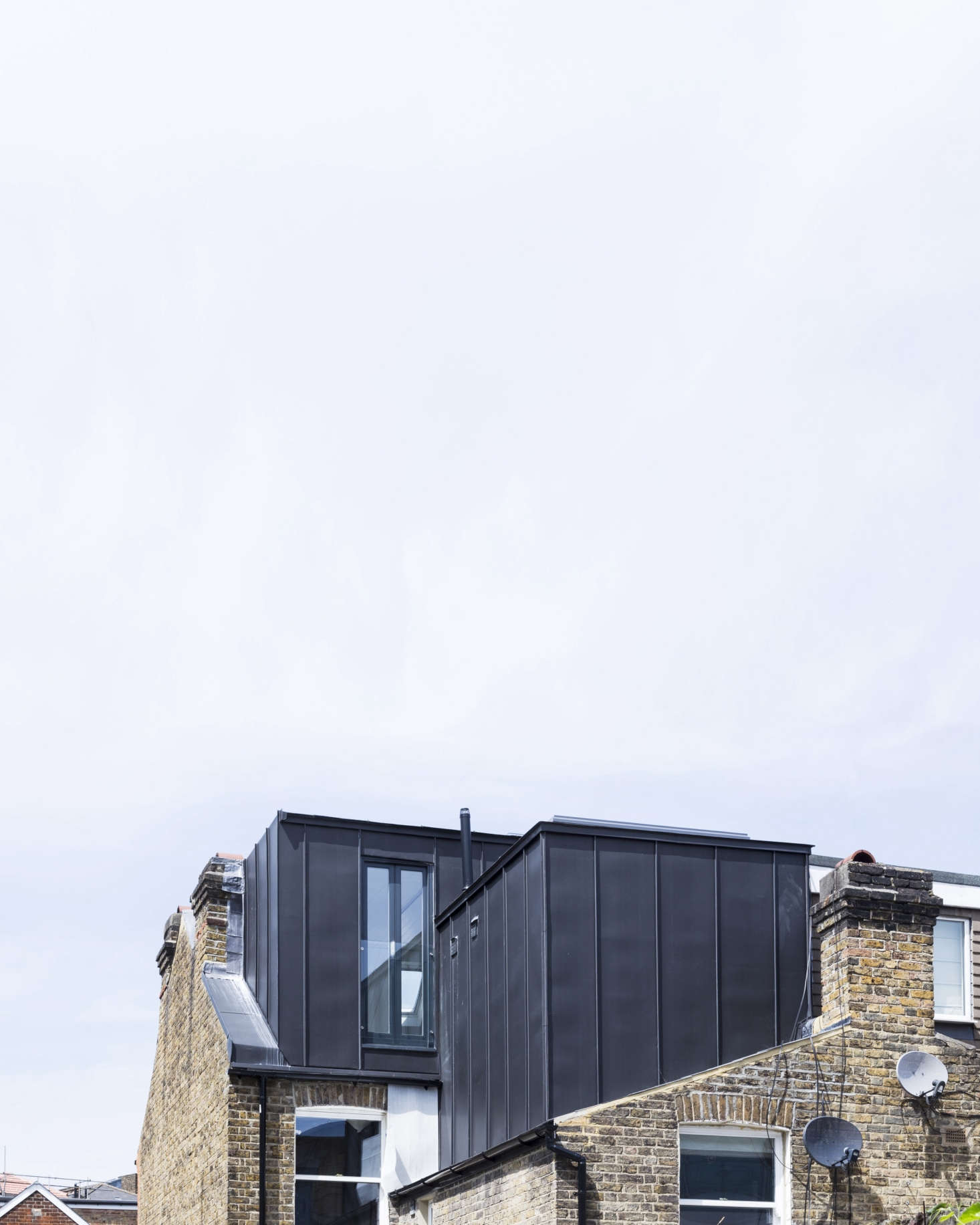 On the roof, two standing-seam metal additions extend the master bedroom and bath. The color was selected to work with the dark gray of the neighboring rooflines.