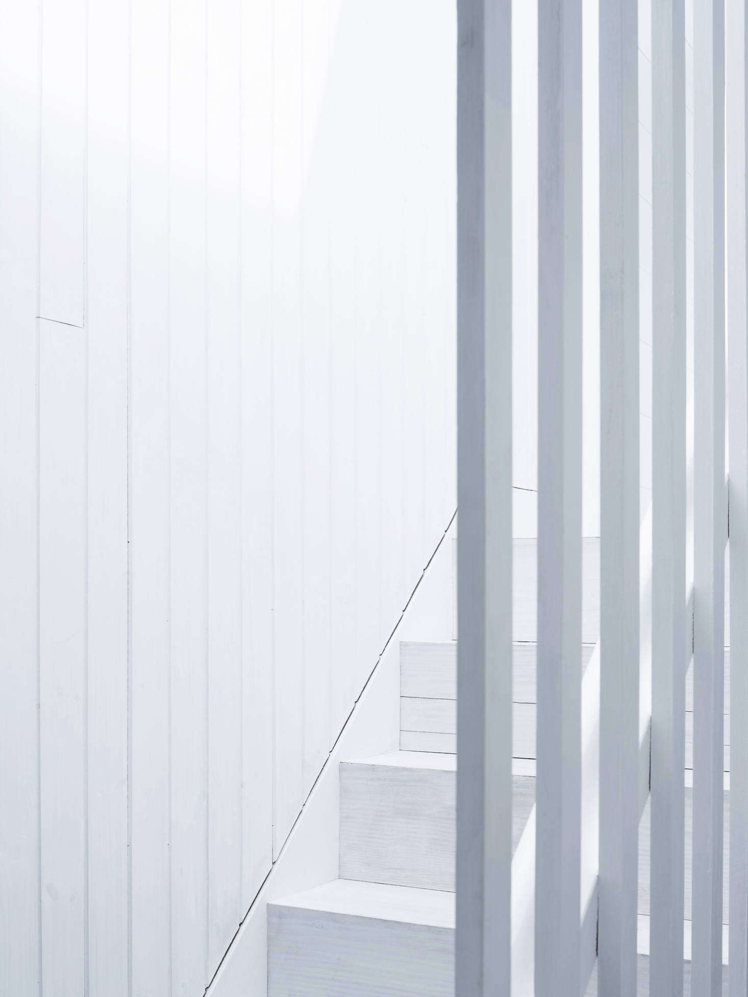 Wood-paneled stairs lead to the four bedrooms Astridge was able to jigsaw into the new upper floor.