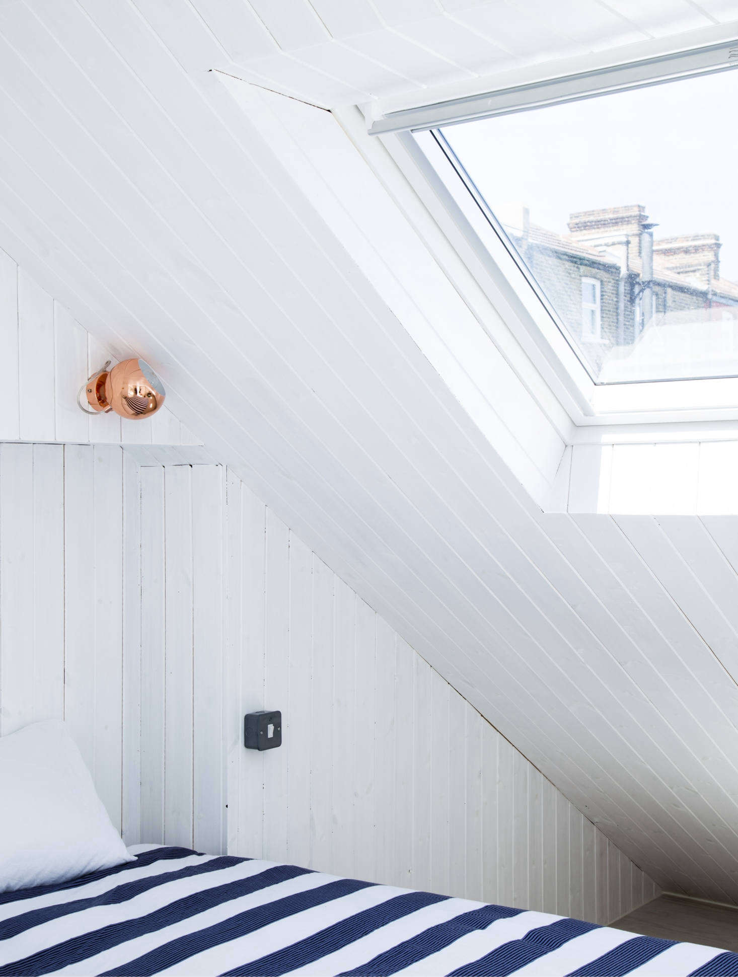 The skylight in the roof is also paneled. The copper sconce was chosen for contrast. For something similar, consider the Benny Frandsen Ball Copper Wall Lamp.