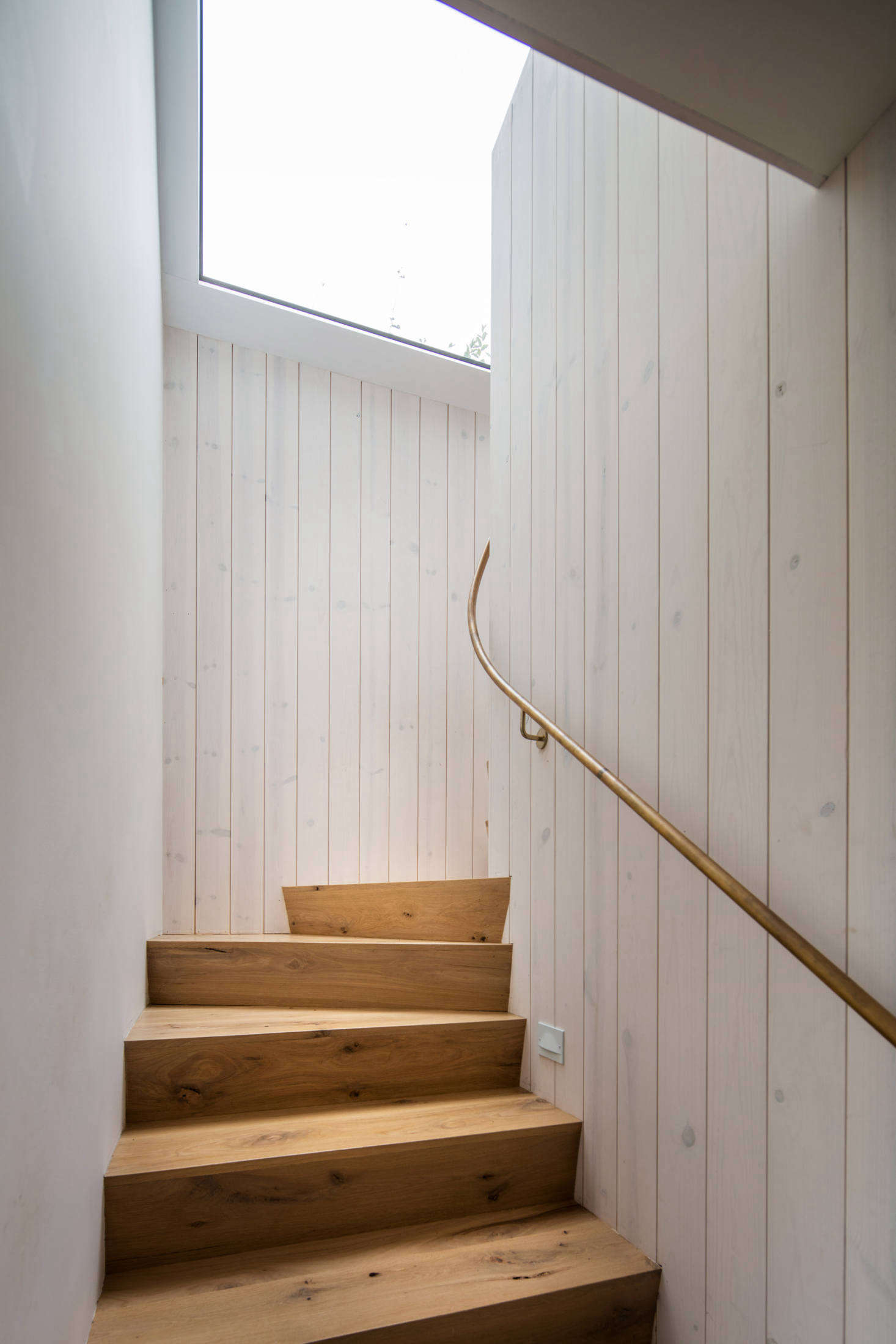The walls on both levels are clad in whitewashed heart pine. The stair rail is made of unlacquered brass.