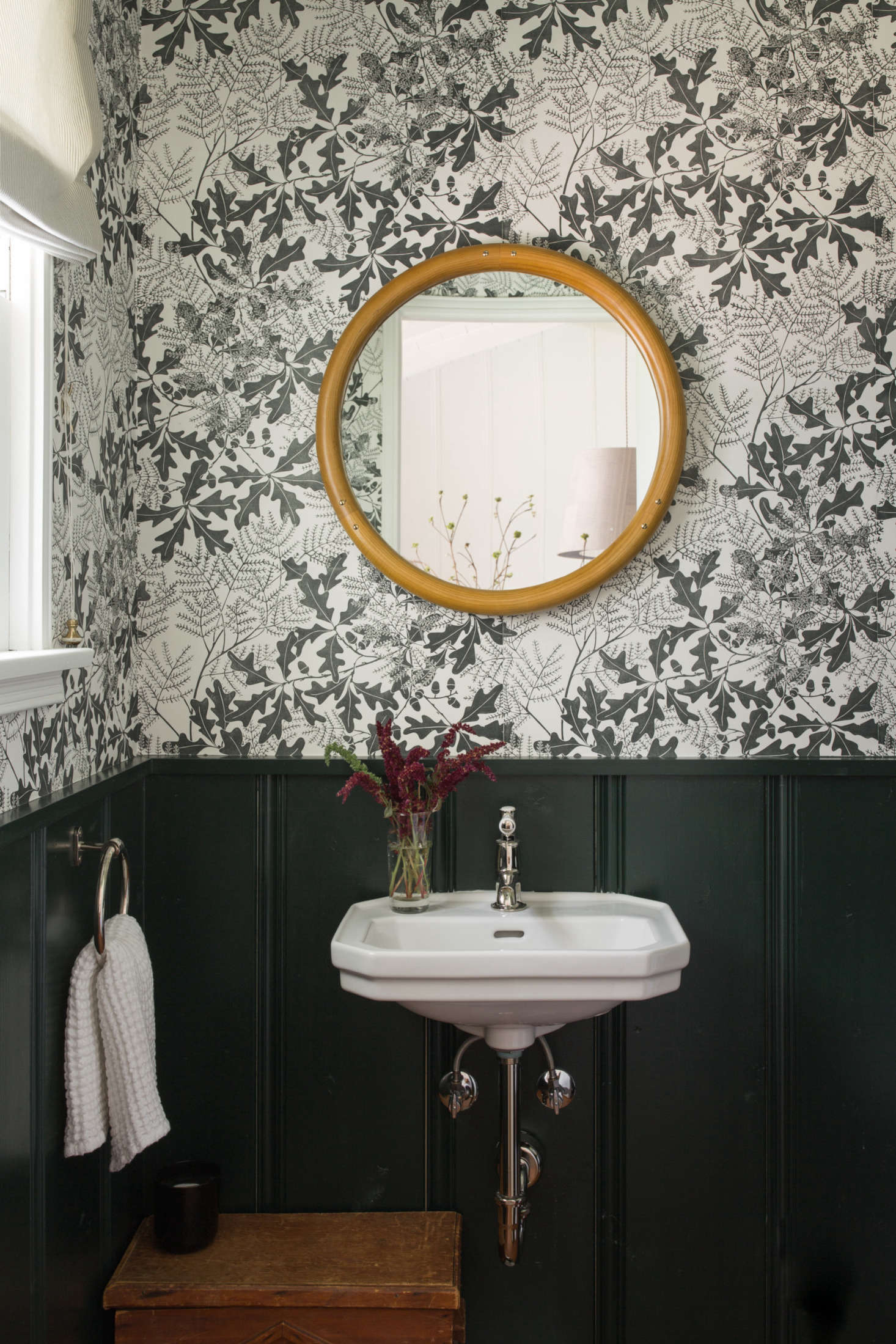 The relocated powder room, with Oakleaf wallpaper by Marthe Armitage from Hamilton Weston. The couple had it custom-printed in an olive green to match the wainscoting, which is painted in Portola’s Troubadour.