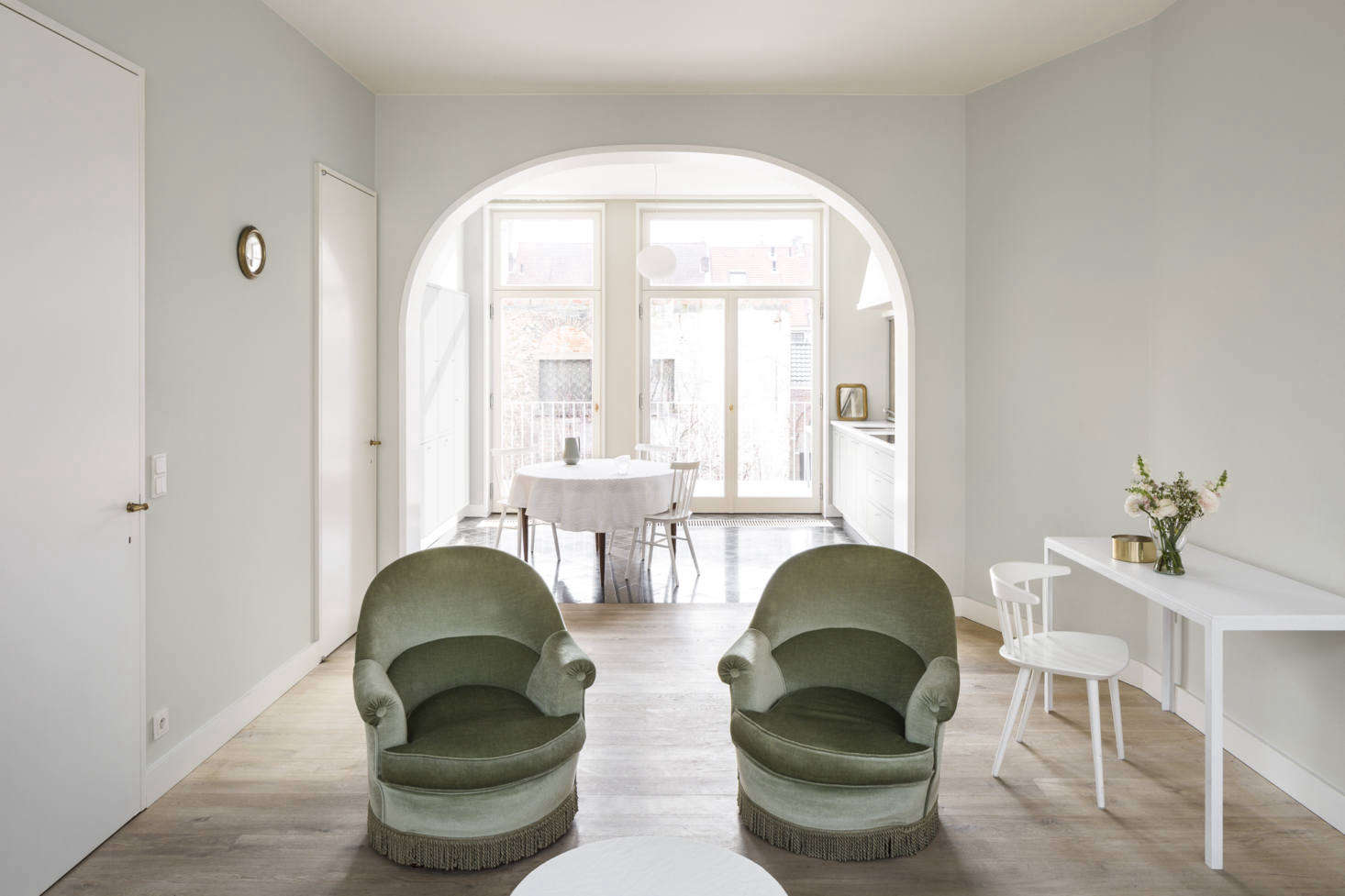 Originally, the interiors were divided into small rooms. “Every flight of stairs was connected to the next flight of stairs with a corridor. This took up an incredible amount of circulation space,” Seghers says. The architects shifted the bones of the house simply but strikingly, moving the staircase inside the wall (at left) and behind a door, allowing the living room and kitchen to be open and uninterrupted. Moving the living areas to the higher floor also means they get “more light, more sun, better privacy, and a view into the trees and leaves.”