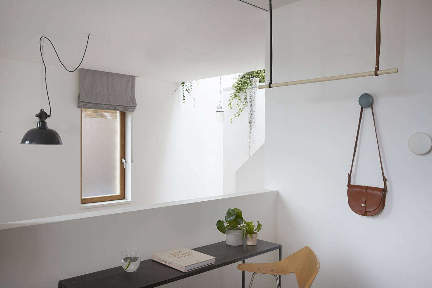 In lieu of trying to squeeze a closet into the space, Hutchinson opted for another flexible, deconstructed solution: a custom clothes rack made of wood, leather straps, and nails, which can hold clothing when the room is used as a guest bedroom but is unobtrusive when it