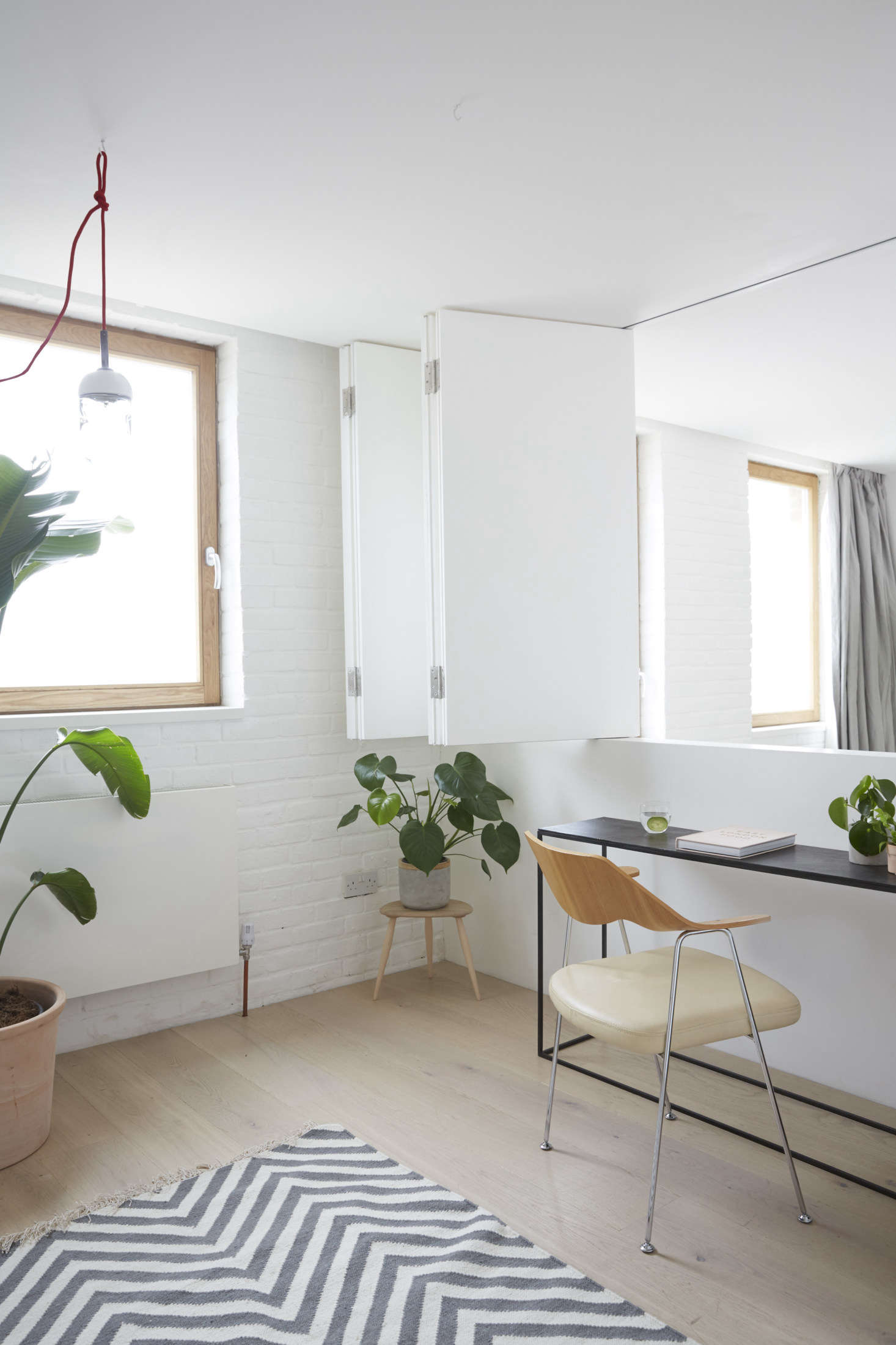 Up a small set of steps in the office/bedroom, shown here with the accordion doors open. Hutchinson added large timber windows fitted with frosted glass, for extra privacy for the young family. The floors throughout are white-stained oak.