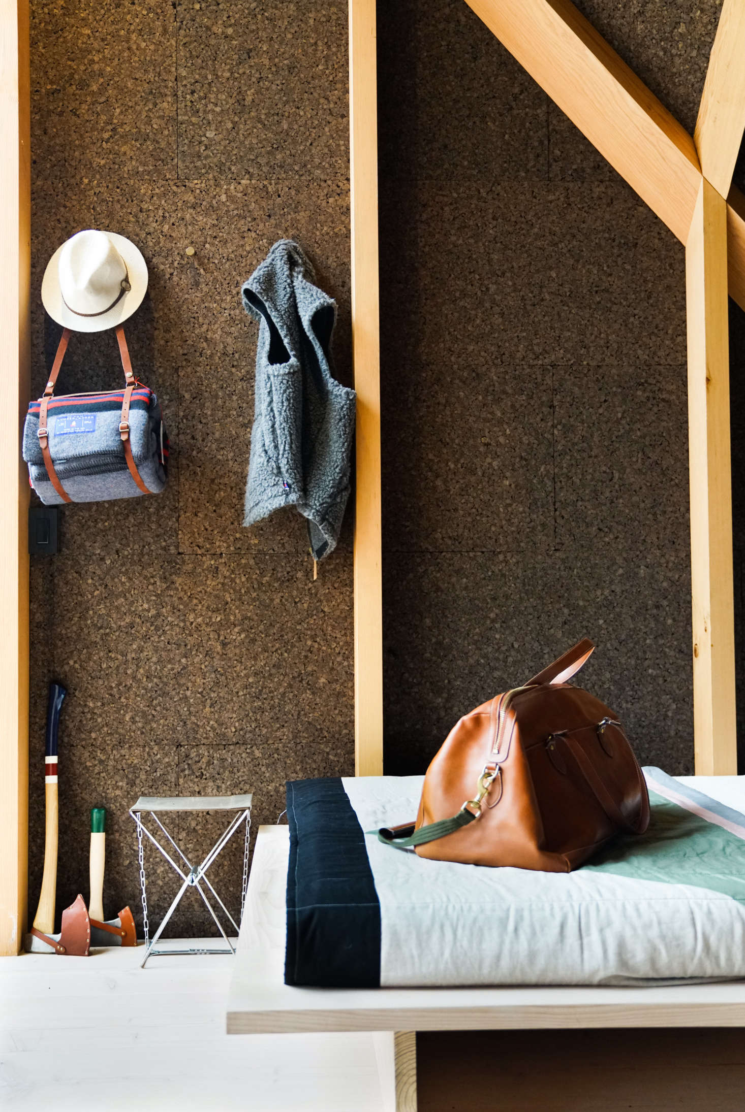 The walls are lined in dark brown cork, which, in addition to being a natural insulator and sound absorber, adds an organic, textured look. The quilt is a Søren Rose Studio design made from Kvadrat fabric. Admiring the camp gear? The hanging Lumberlander Blanket, painted Axes, and The Waxed Canvas Camp Stool are from Best Made Co.
