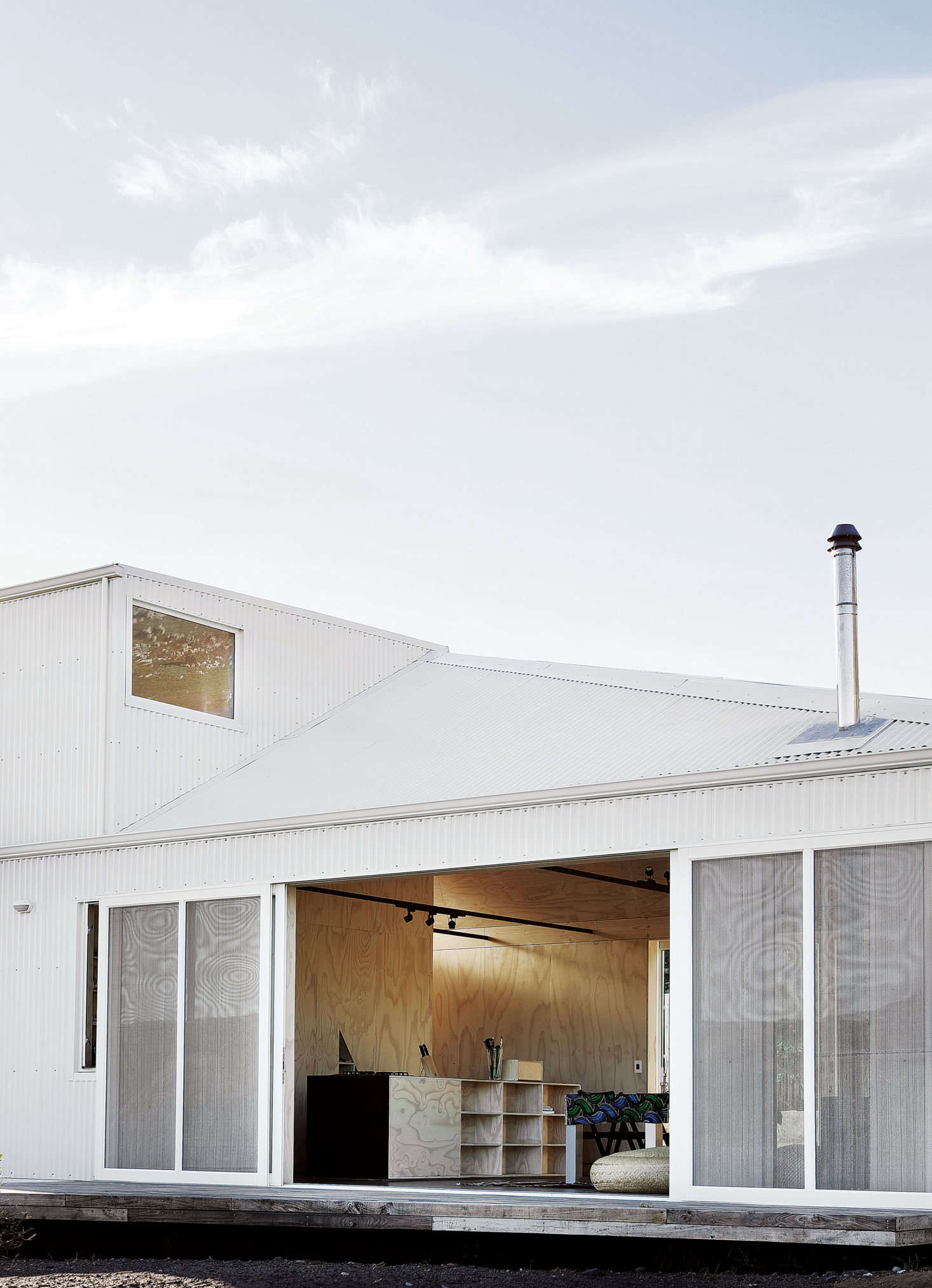 The communal living space in the house has matching sliding doors on either side. “They act as a bridge between the courtyard behind and the view. By closing one side you can cut out the wind but still enjoy the view.” The deck is built with Sugar Gum, an invasive tree species to the area, put to use here in lieu of tropical hardwood decking.