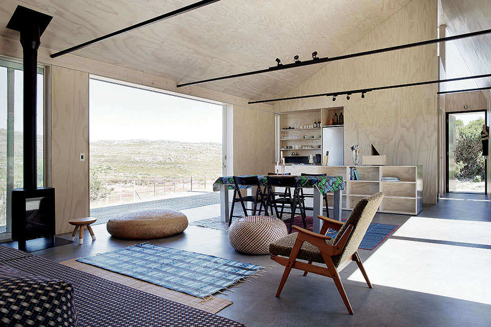 The floors throughout the house are Corcoleum Malpette flooring, a hardwearing composite material made from recycled wood chips. The living and dining spaces are layered with African rugs. The fireplace is a Danish Jøtul GF 160 Gas Stove.