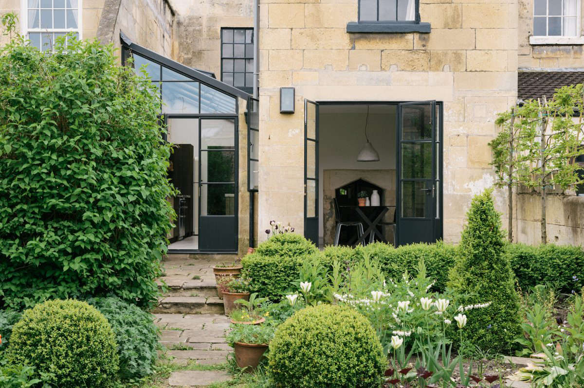 The house is part of a series of connected cottages. Steel-framed French doors open the dining area to the enclosed garden, framed at one end by a Bath stone wall. The couple reused stone to build the back terrace. 