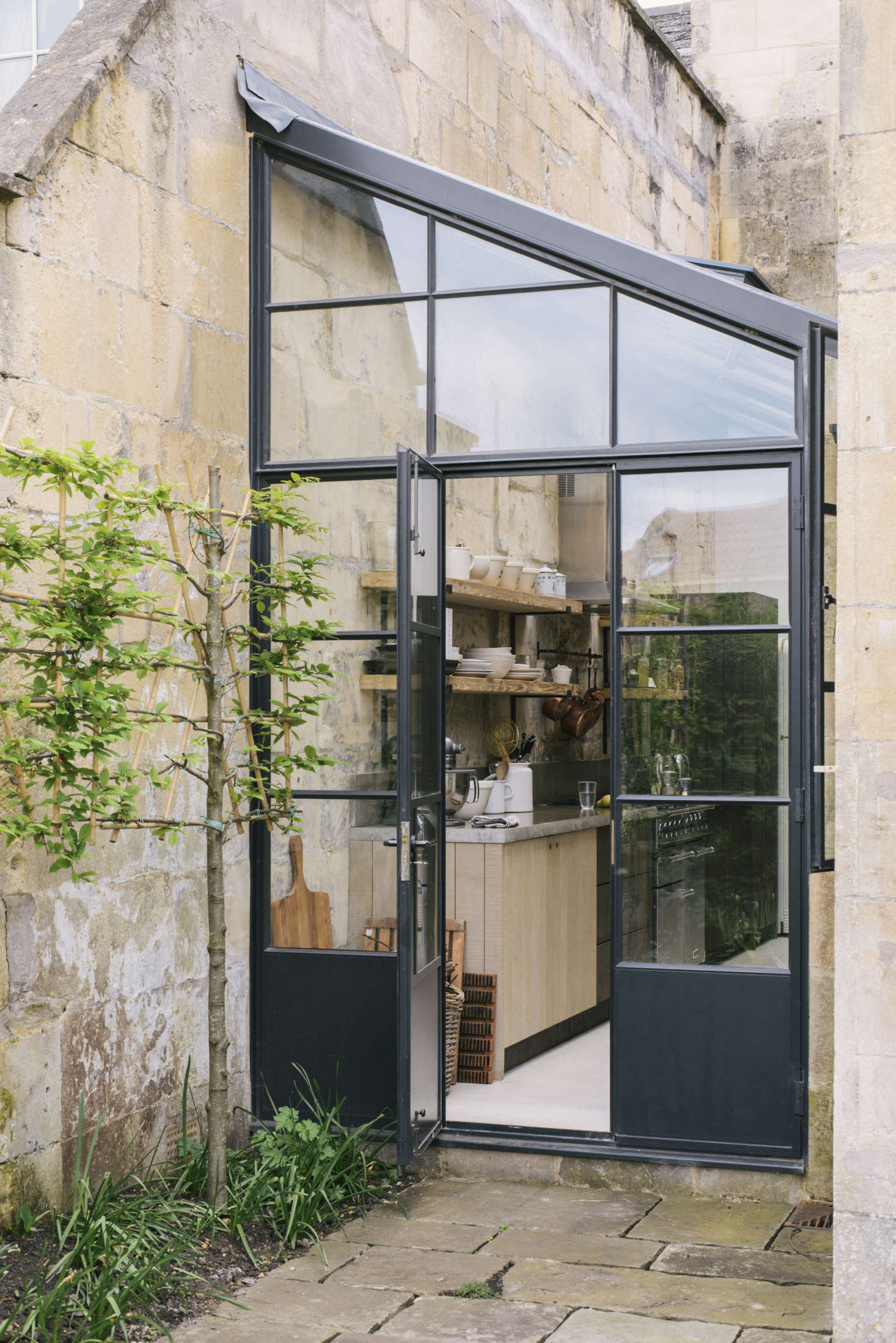 The greenhouse-style extension is fitted between two wings of the house (scroll to the end to see a stepped-back view). The couple worked with Mark Watson of architect-surveyors Watson, Bertram & Fell to draw up plans and secure building permissions; the bespoke steel-framed doors are by Fabco.