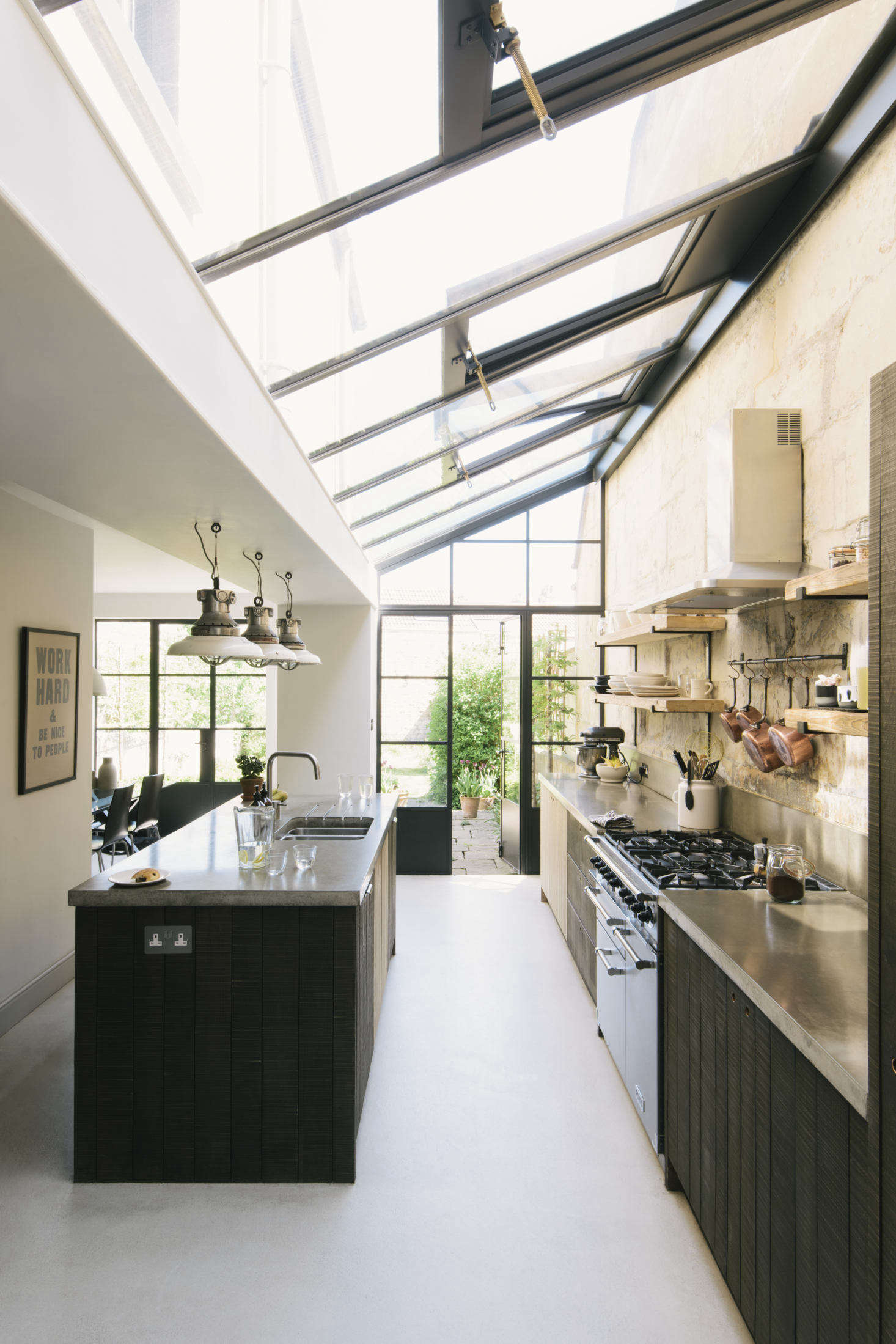 An original Bath stone wall runs from outdoors to in. The island that runs parallel to it creates a setup from which Michael can work while entertaining guests in the adjoining dining area.