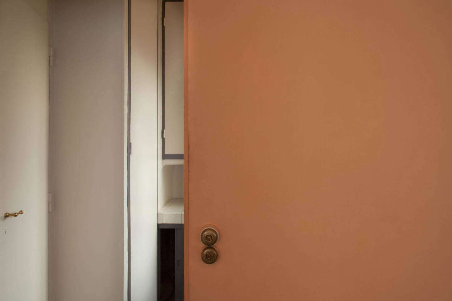 A polished brass door handle and unlacquered brass light switches in the dining room.