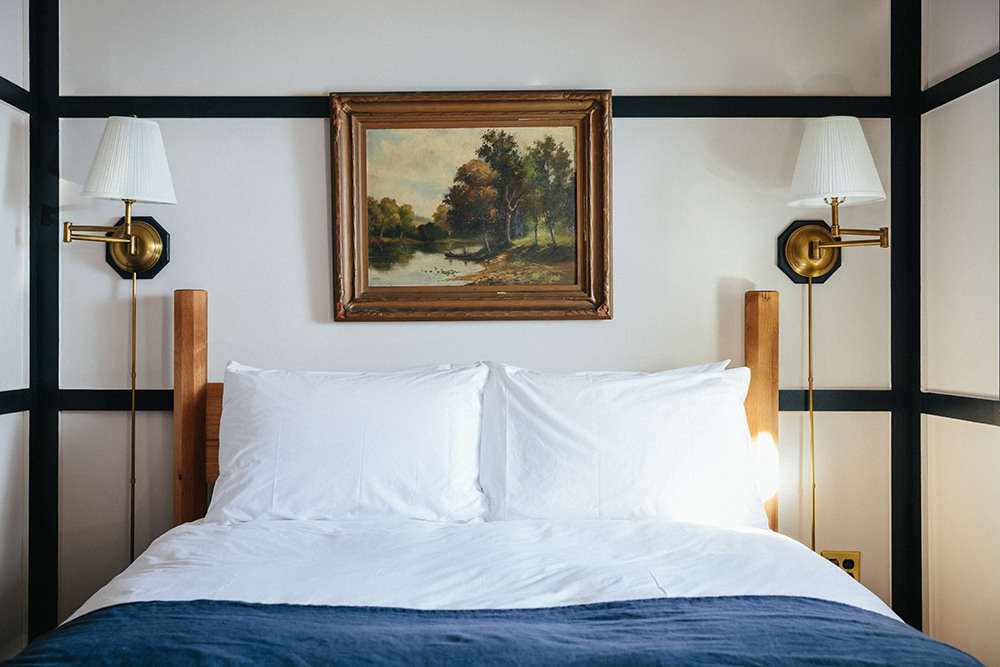 Twin brass swing-arm sconces with shades flank the bed, cords and all.