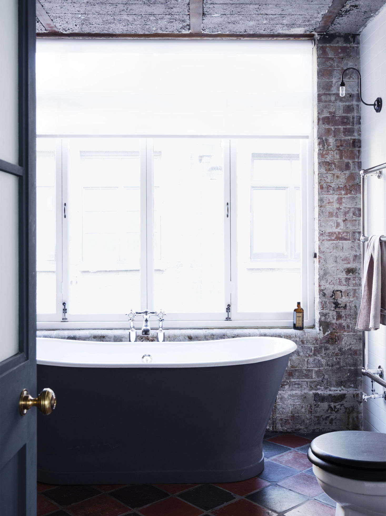 A sleek soaking tub and exposed brick wall create a feeling of laid-back luxury in London.