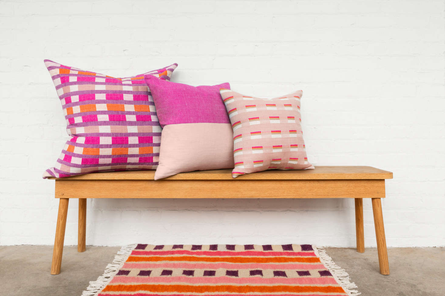 The cerise colorway, shown here in three sizes. The Omo Valley Collection pillows are priced between $5 and $0. The cerise Bana Rug is currently sold out, but it is still available in sable and azure for $5.