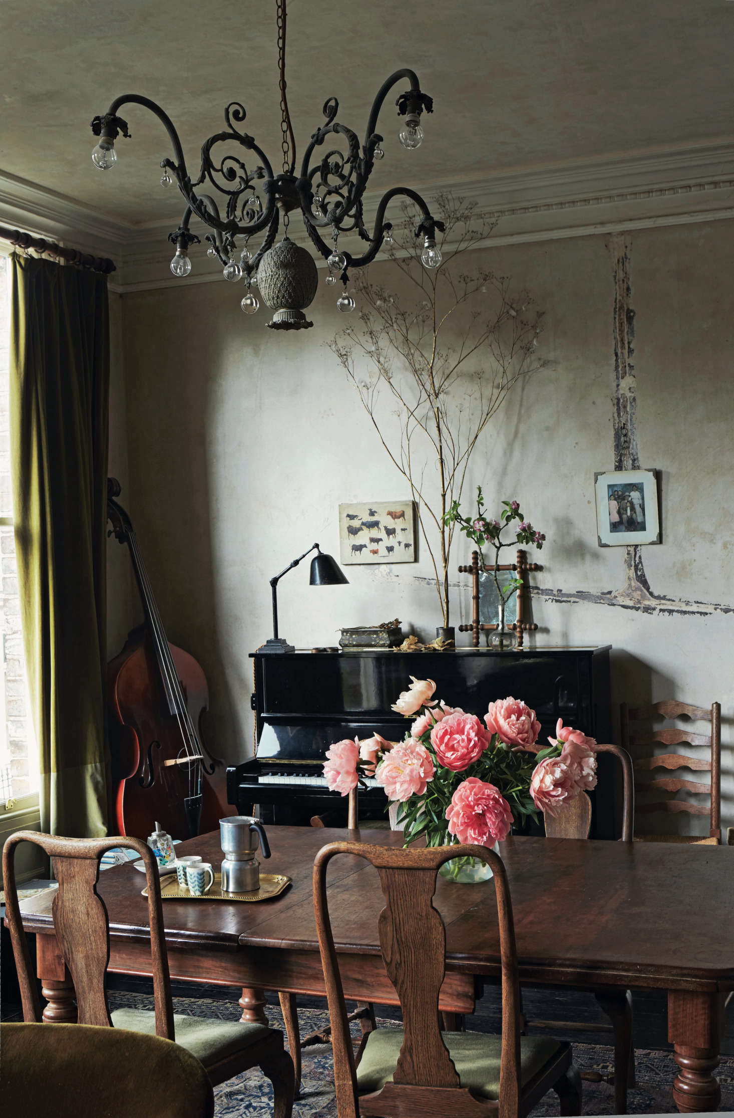 In Perfect English Townhouse, Ros Byam Shaw notes that the lines of filler on the stripped wall above the piano “mark out where the pipes for the gas lighting once ran.” She goes on to explain: “The chandelier is one of David’s creations, and incorporates a metal pineapple found at a car boot/yard sale. The painting of cows on the far wall is a study by David’s great-grandfather, the celebrated Swiss artist Eugène Burnand.”