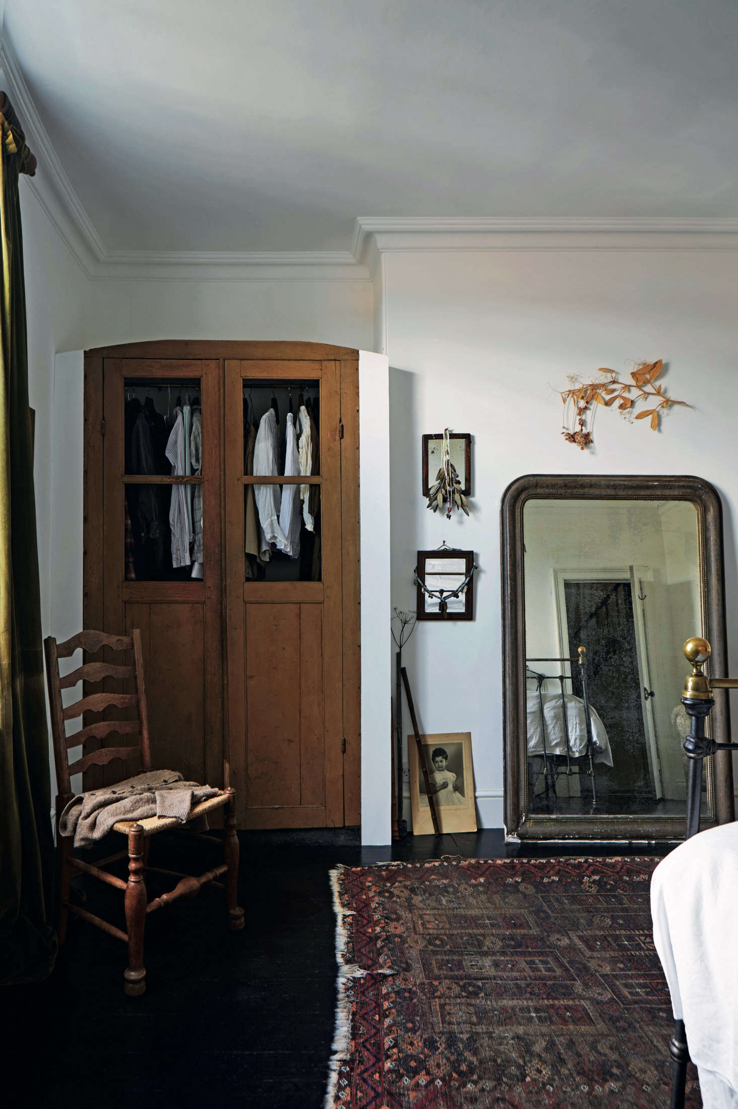 In the master bedroom, the couple inserted an antique wardrobe into a niche, and leaned a mantel mirror against the wall.