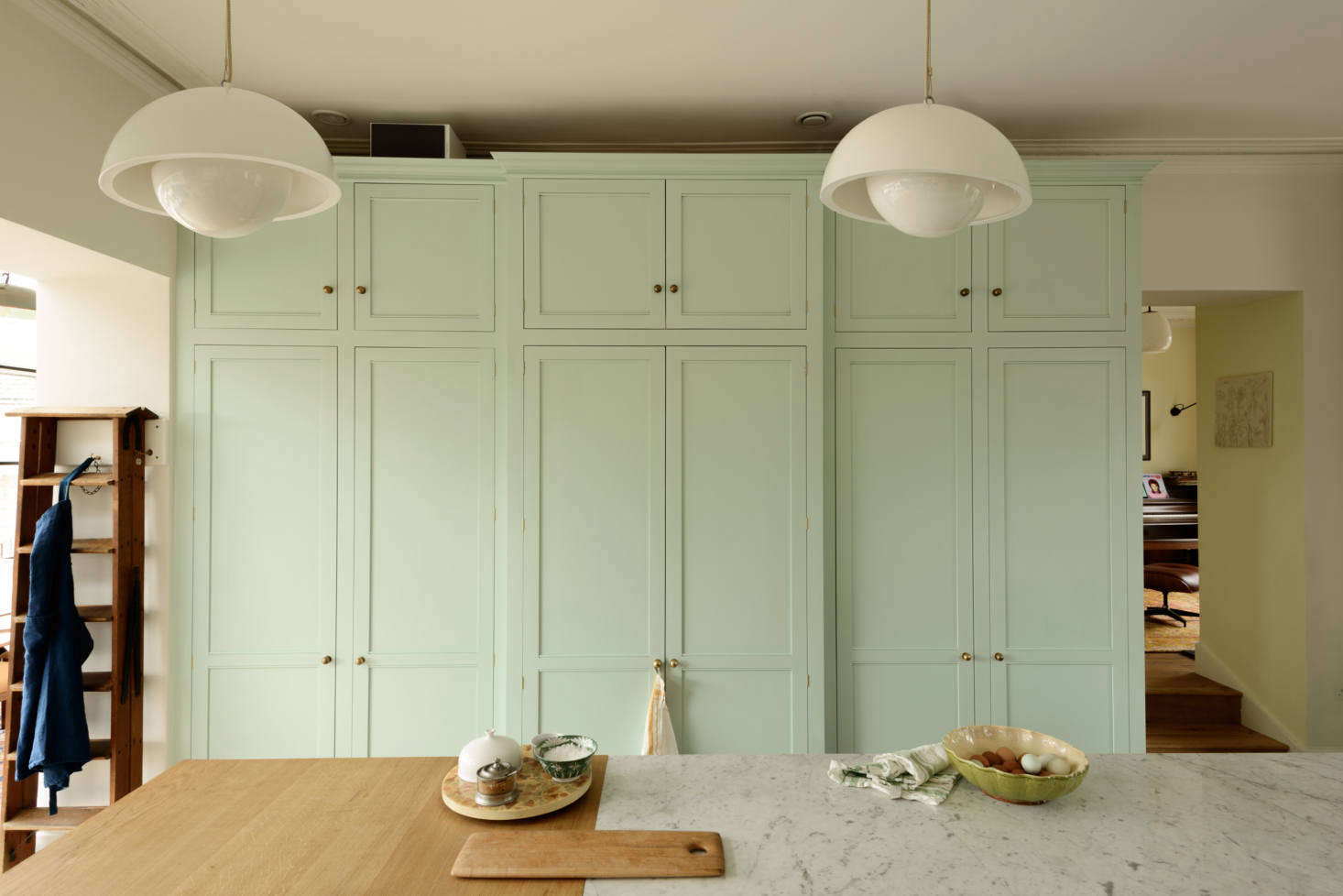 By closing up an existing entryway into the next room, we gained extra depth for a walk-in pantry in the center of the storage wall, for things like the aforementioned cereal boxes. It’s flanked by an appliance cupboard (left) and fridge and freezer (right).