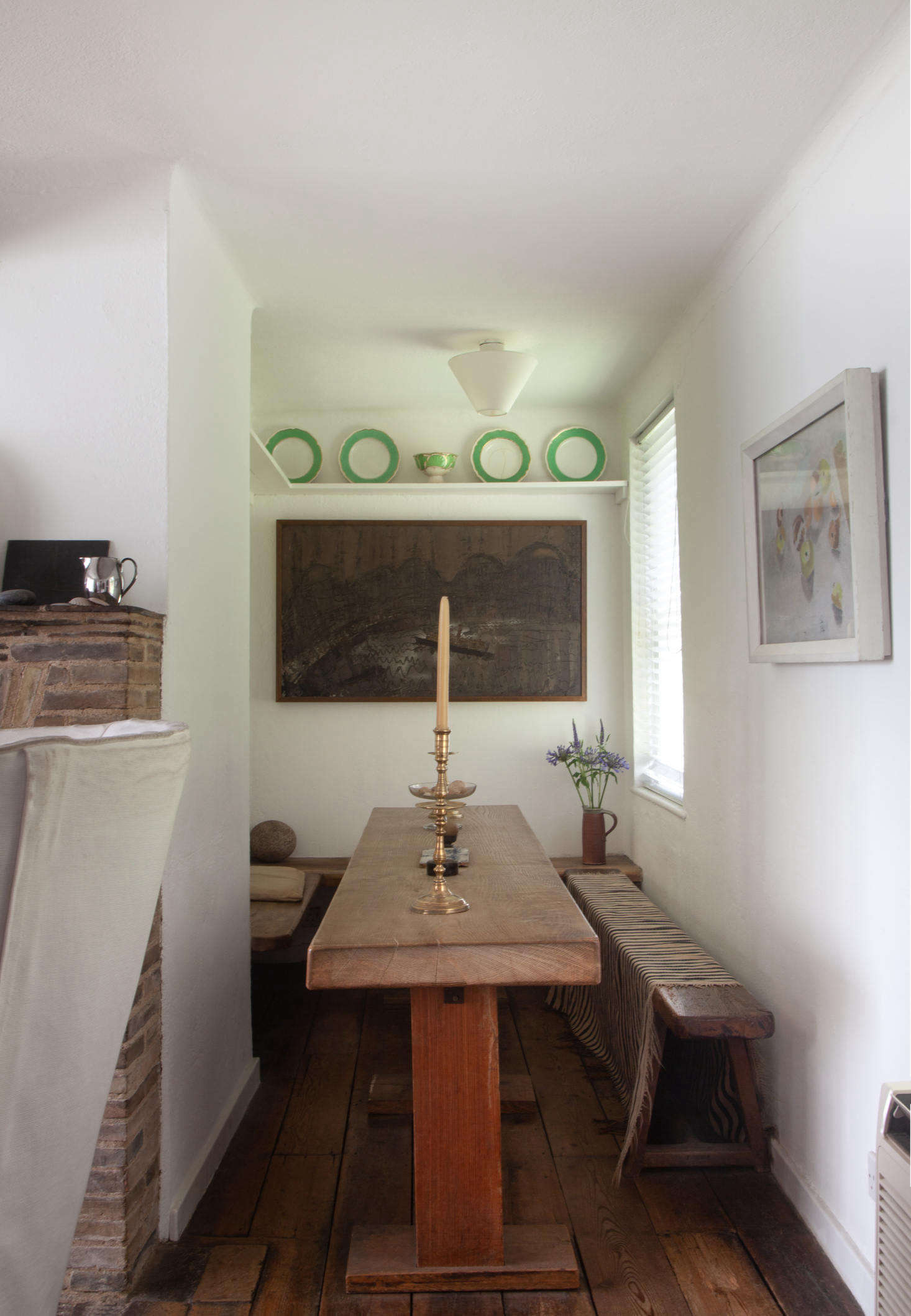 A dining room corner in the original cottage includes a slender table and a textile-draped bench.