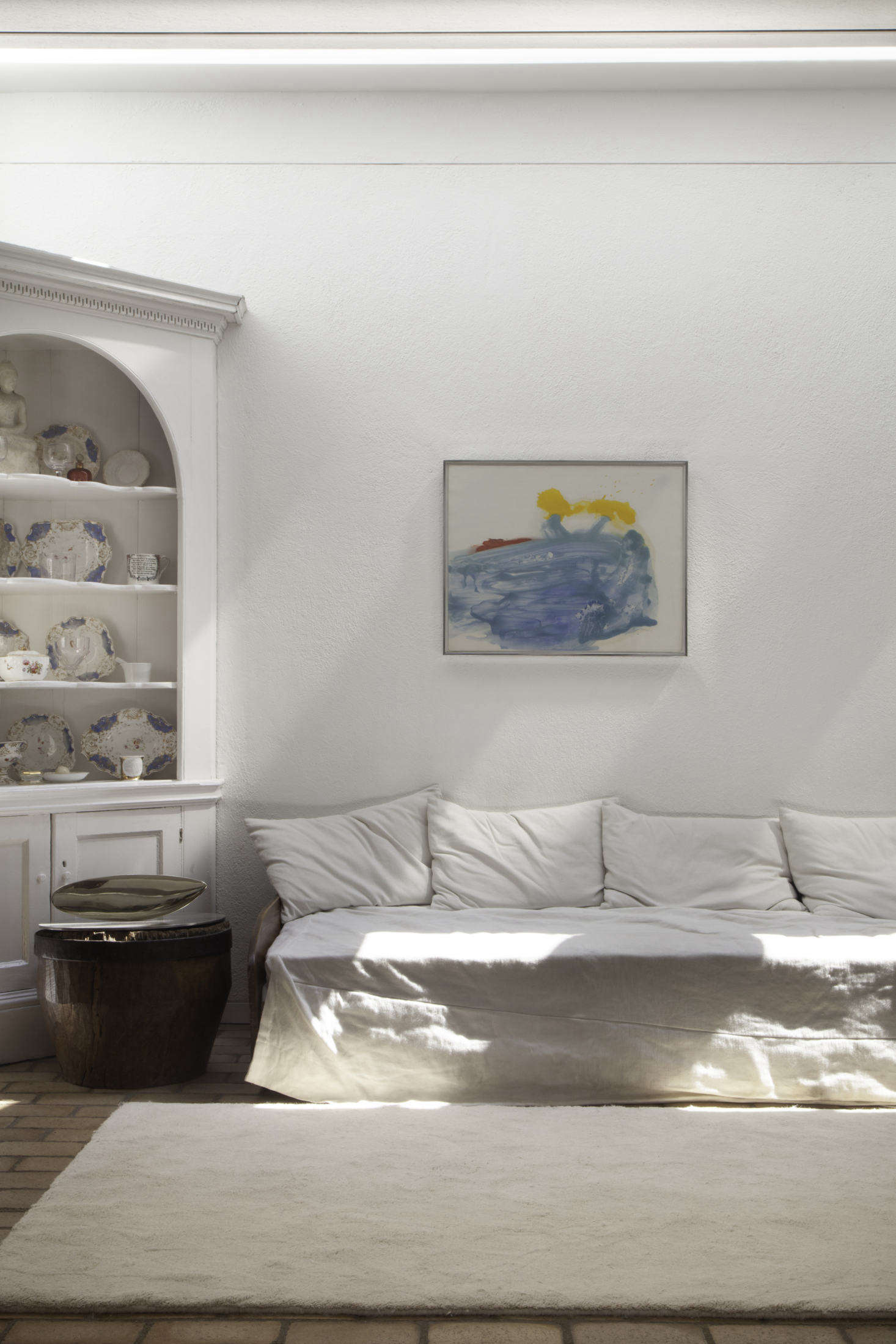 A white-painted corner hutch with blue, gold, and red china meets Helen Frankenthaler