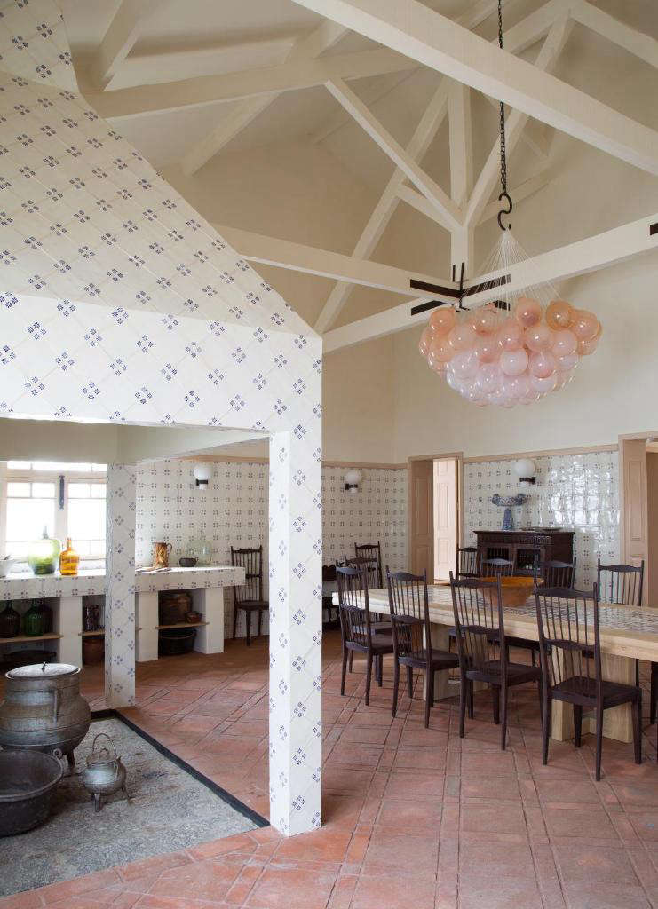 In the combined kitchen and dining room, walls are tiled in traditional Portuguese azulejos. For the pale-pink glass light installation, Yovanovitch collaborated with Swiss glassmaker Matteo Gonet.
