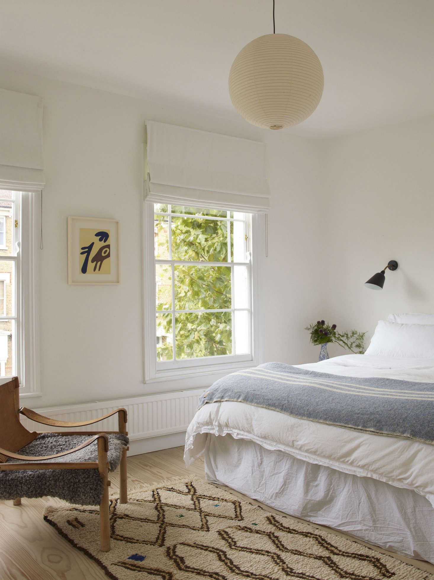 A sheepskin is draped on a leather campaign chair. A Noguchi Akari Lamp adds a sense of sculpture, above.