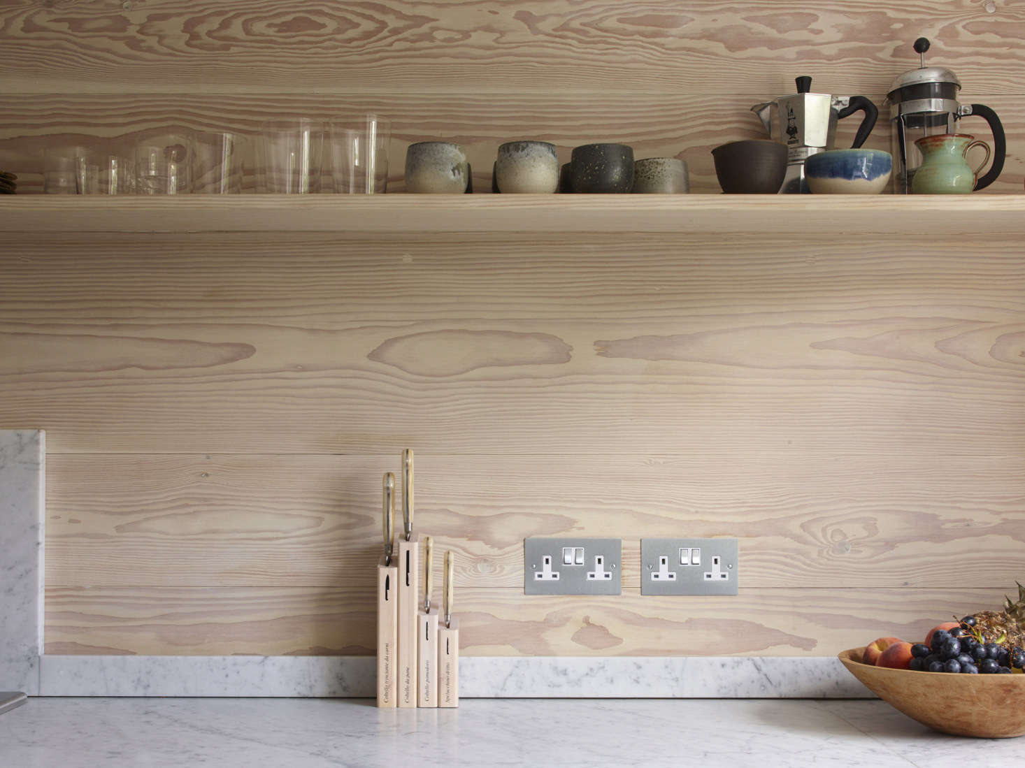 A thin wood shelf stores French presses and cups by K.H. Würtz.