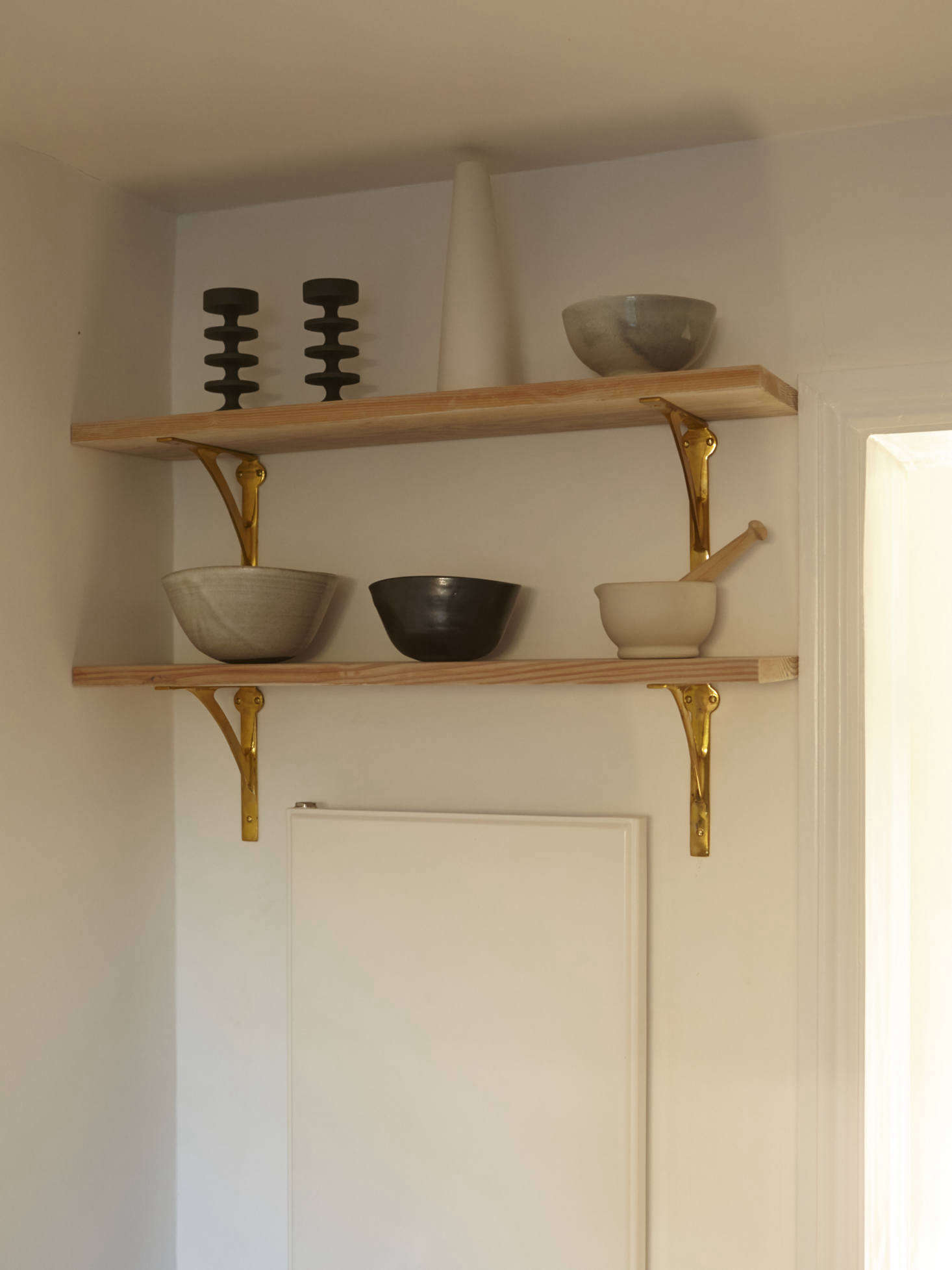 High shelves hold sculptural ceramics (and make use of the space above a wall unit).