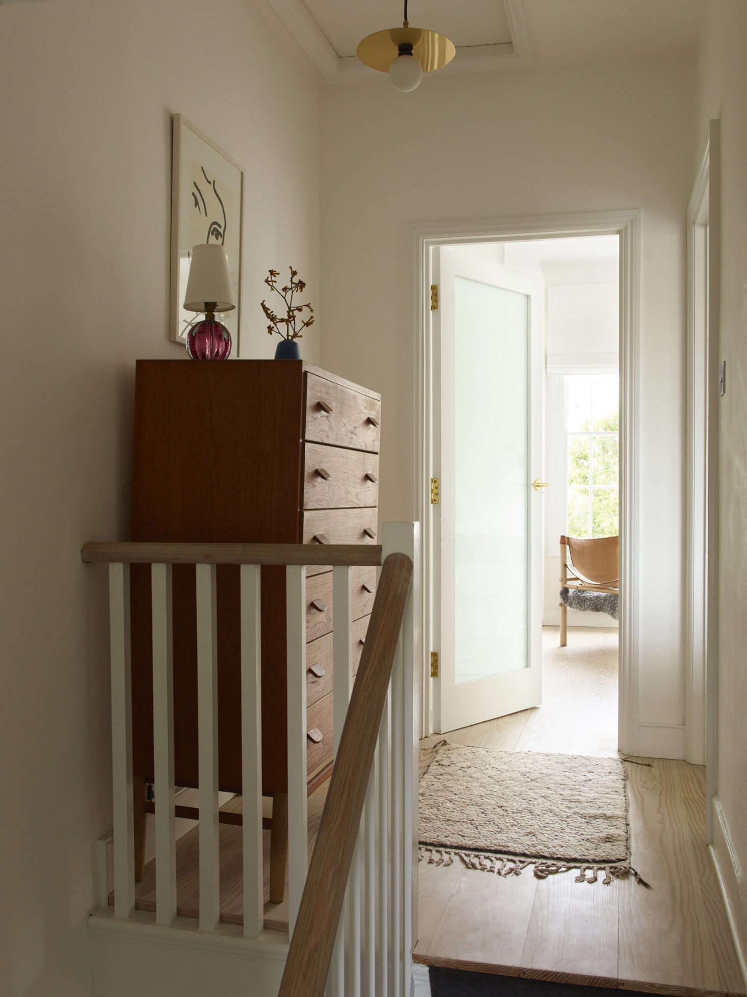 At the top of the stairs: a hanging pendant by Atelier Areti and, on the dresser, a pink Murano glass lamp from Etsy.