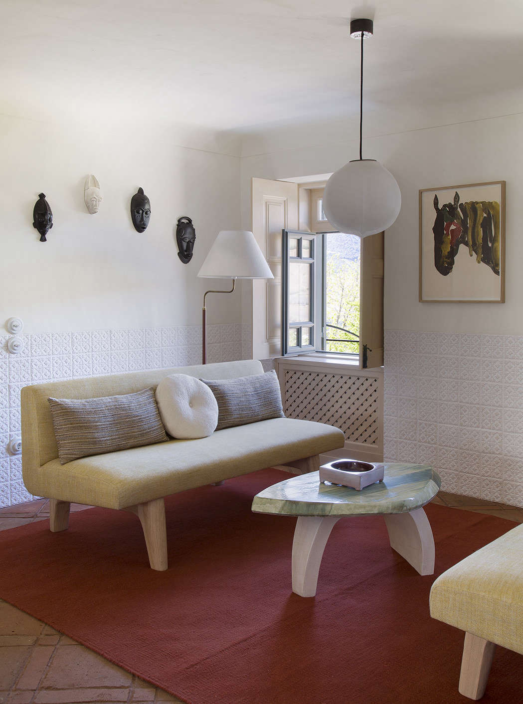In a small living area off of the kitchen, a vibrant rug sets off a surprising palette of pale yellows and greens. The table is a collaboration between Yovanovitch and ceramist Armelle Benoit.