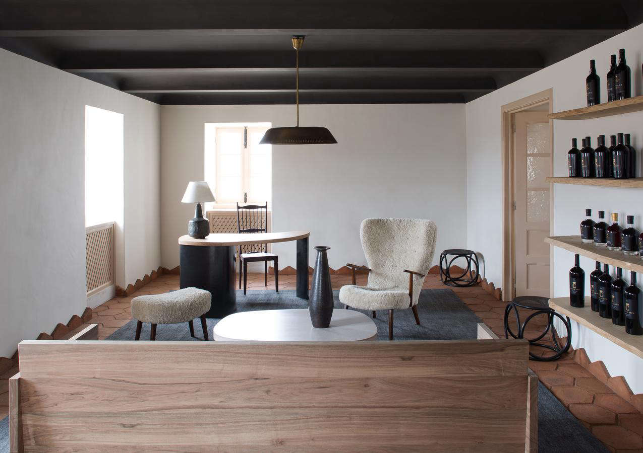 Another living space in a cohesive color palette, with a black-painted ceiling and black rug. The sheepskin chair is Yovanovitch’s own design, and on the shelves are the winery’s own bottles. Note how the floor tiles continue up the walls, into a geometric baseboard of sorts.