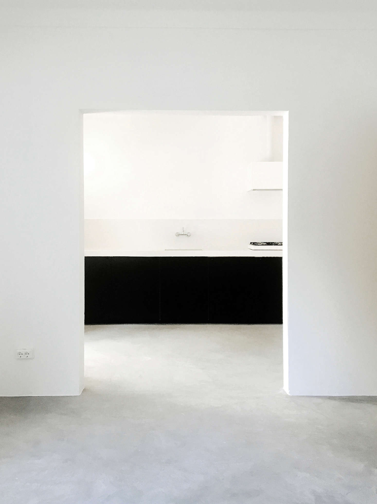 A lesson in sparseness: A wide, sculptural doorway leads into the kitchen. Because the interiors are so spartan, Bento chose the limited materials with care: white-washed plaster walls and matte concrete floors that have a subtle visual texture.