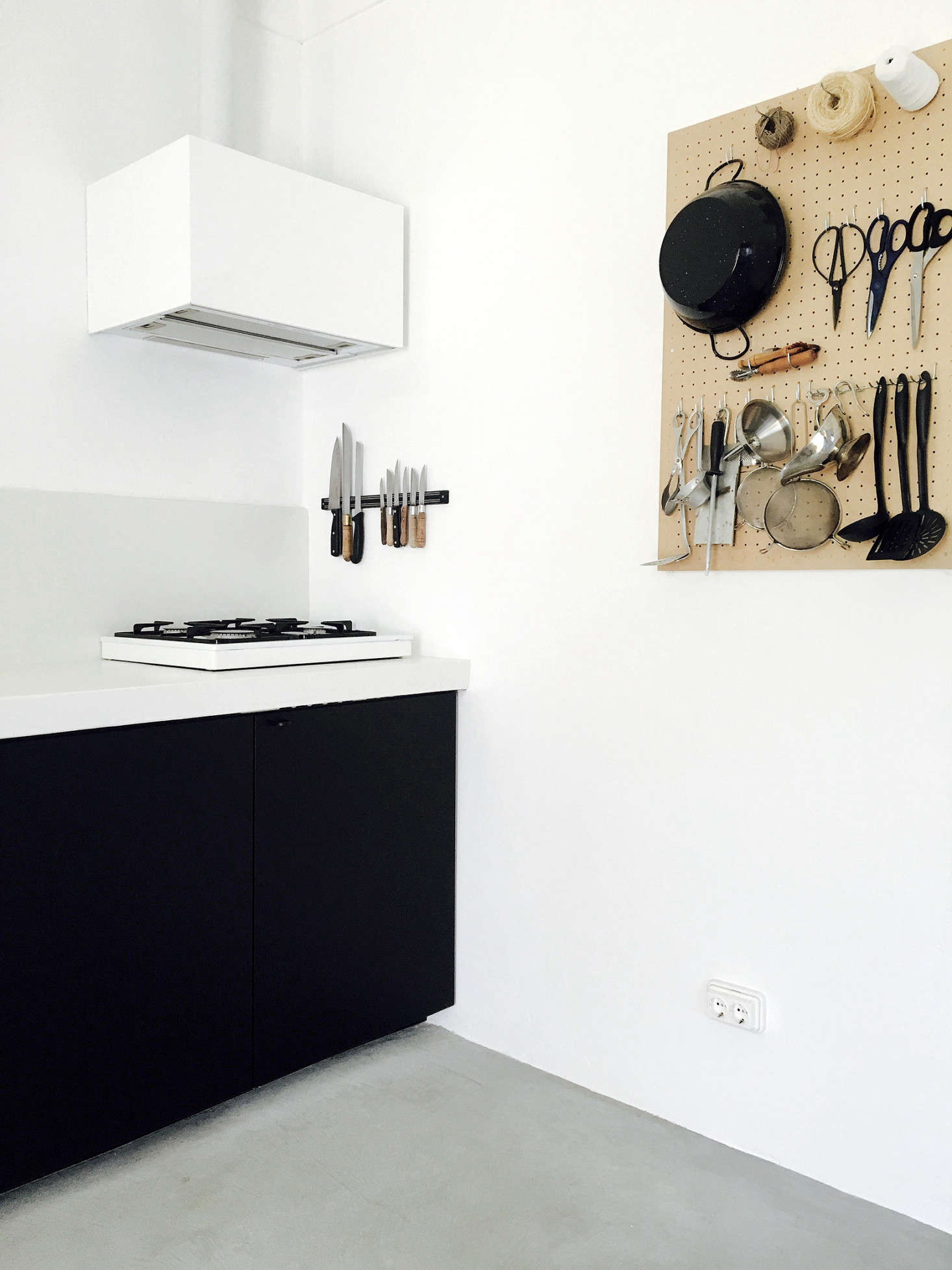 By the small gas cooktop is a well-appointed pegboard, which holds kitchen shears and even a silver pitcher.