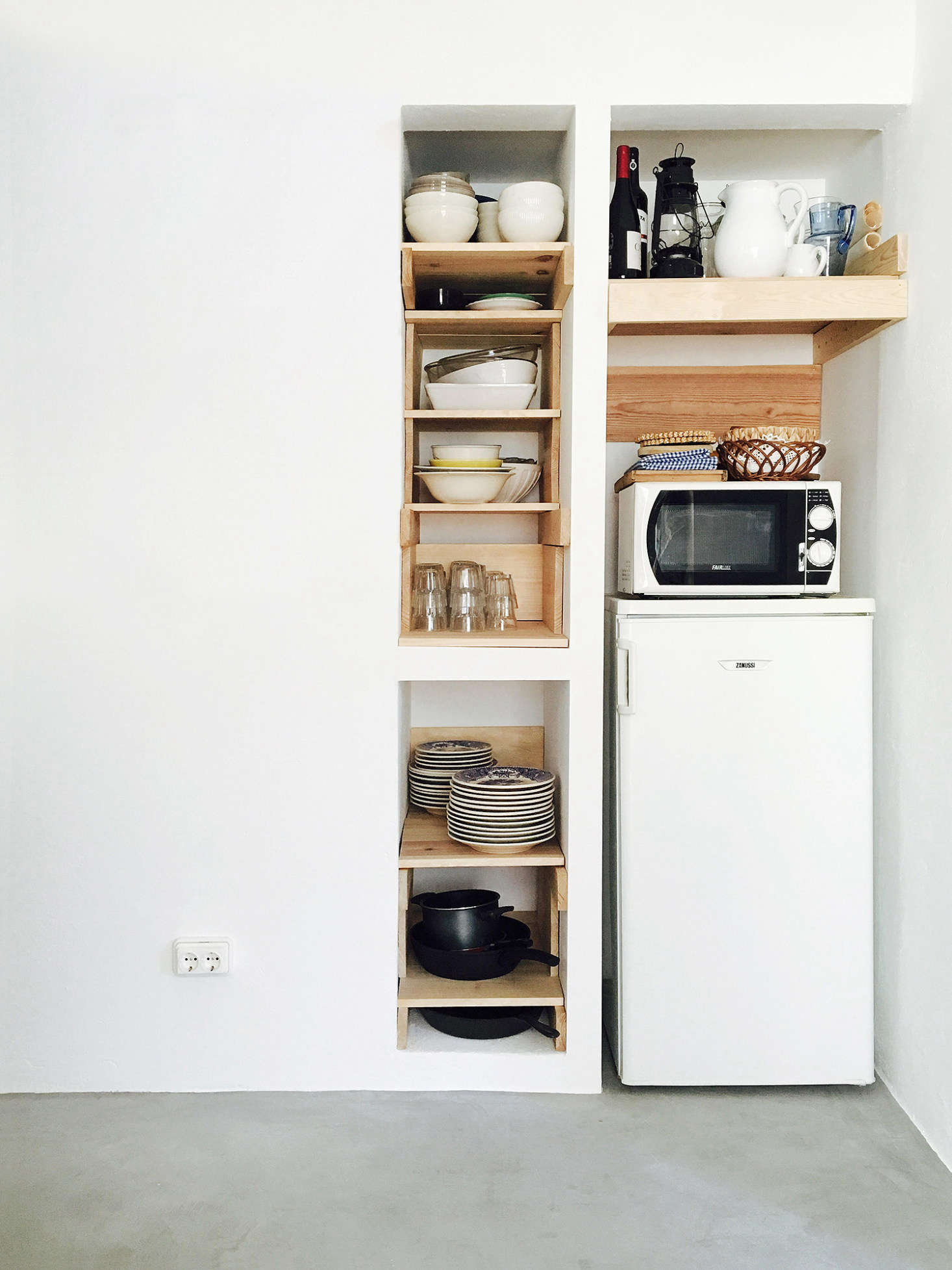 Bento chose waxed woodwork as a third main material, and it’s a theme repeated throughout the house. Here, it forms ad-hoc open storage in a niche beside the European-sized refrigerator.