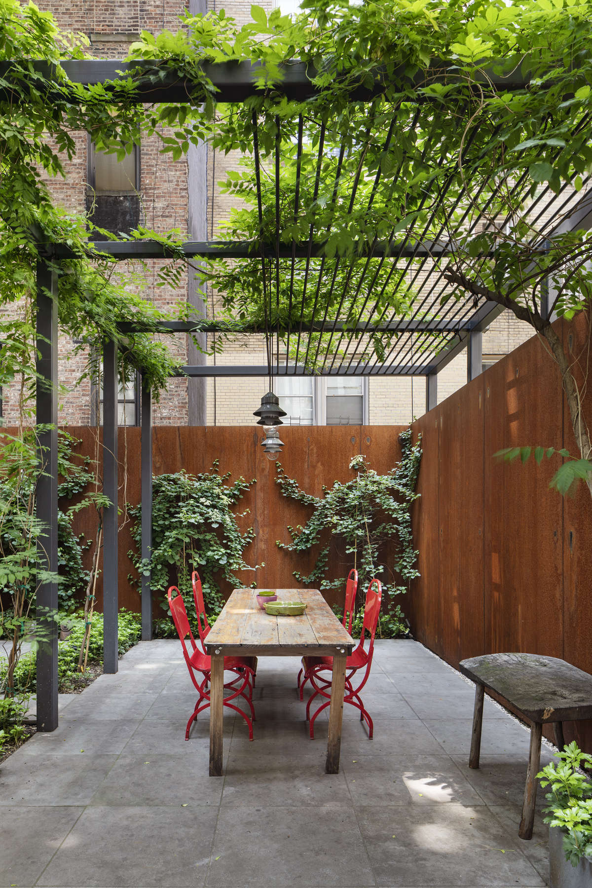 The outdoor space is anchored by a custom steel trellis.