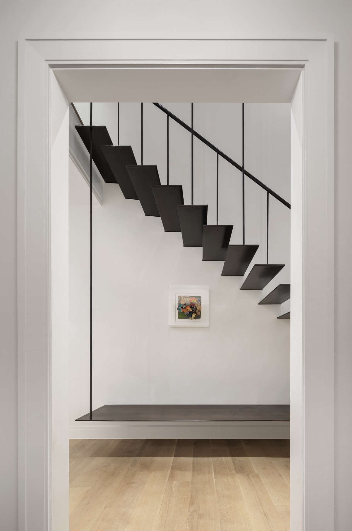Near the front door is a suspended bench, echoing the stairway design, for putting on and taking off shoes. ABR Molding fabricated the entire thing—stairs, rail, and bench—on site.