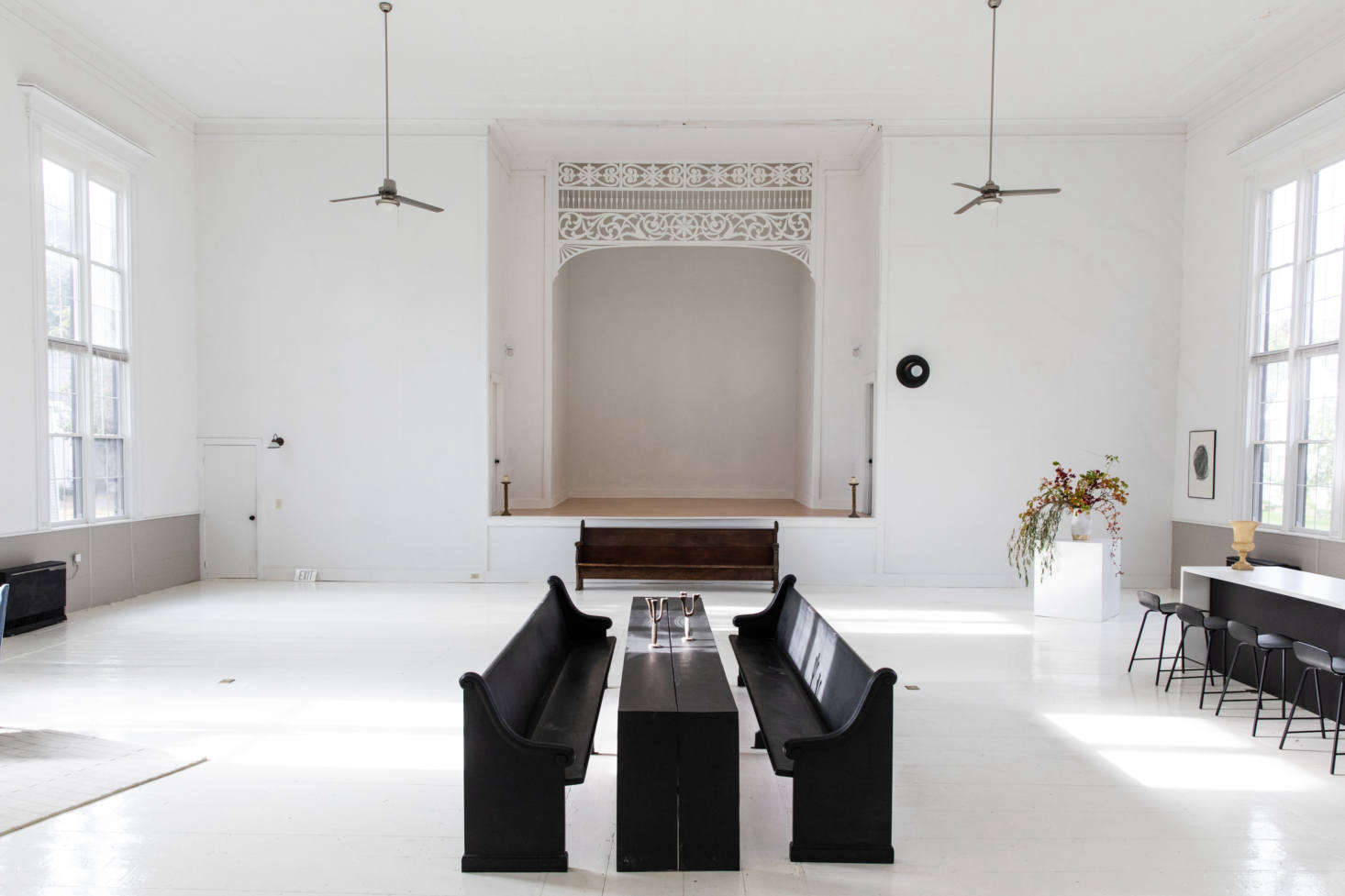 The main room, formerly the church sanctuary, is painted entirely white and appointed sparsely to amplify the expansiveness. The ceilings are
